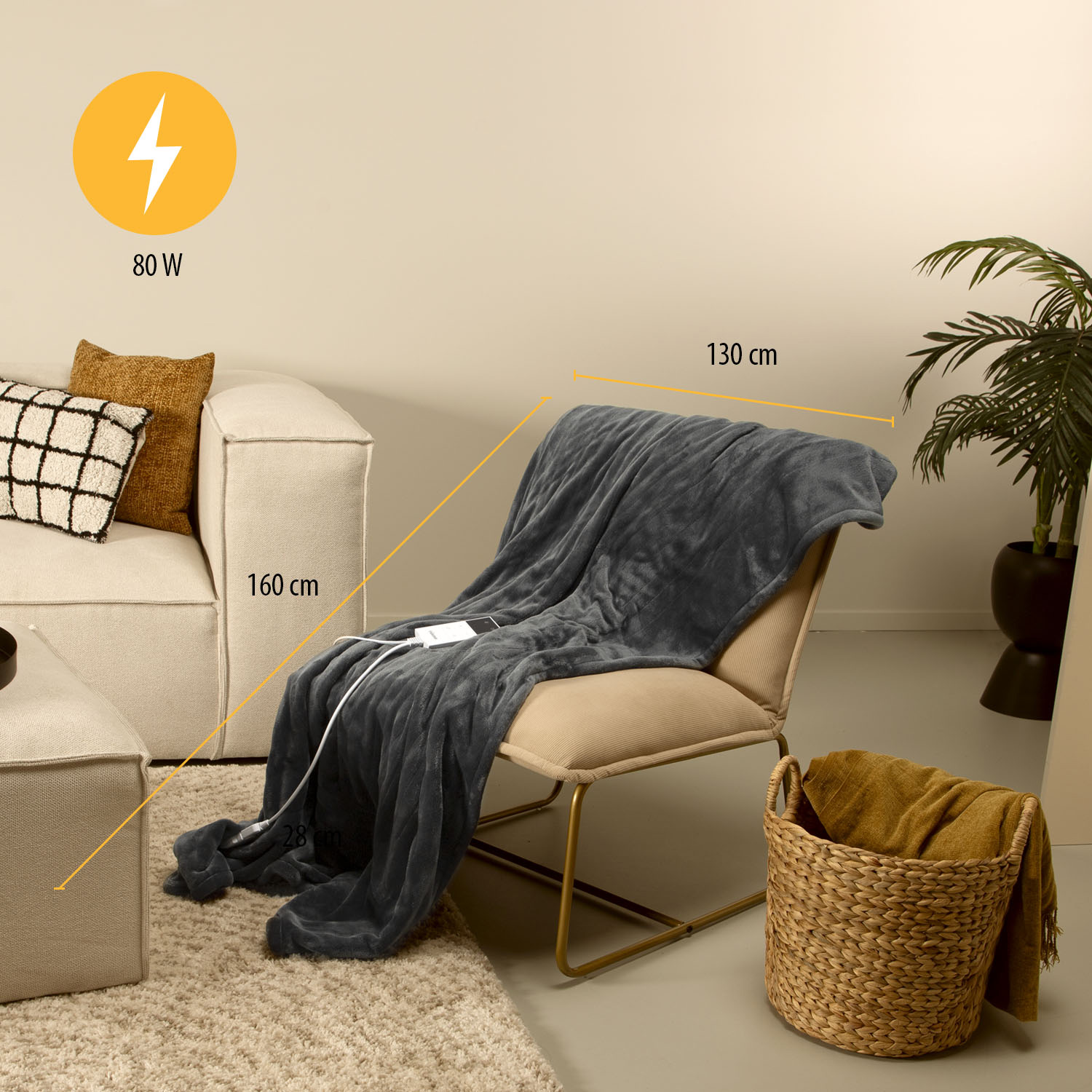 A gray electric blanket draped over a chair. A wicker basket with a yellow blanket sits beside. A sofa is in the background.
