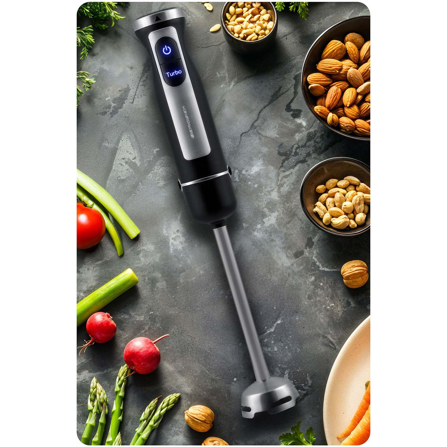 Czarny blender ręczny leży na stole z jedzeniem, w tym orzechami, warzywami i rzodkiewkami. Blender ma srebrny i czarny design.