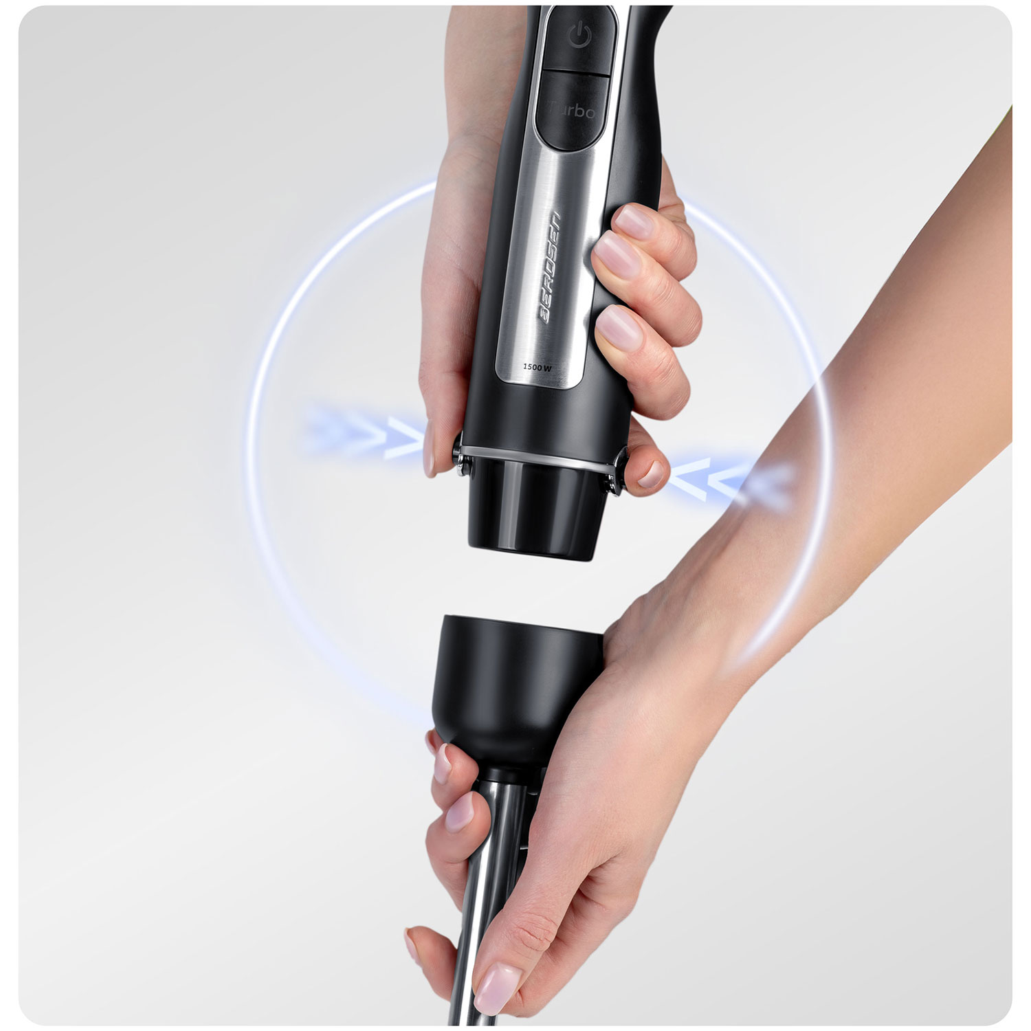 Ręce składające czarny i srebrny blender ręczny. Górna część trzymana jest w jednej ręce, dolna w drugiej.