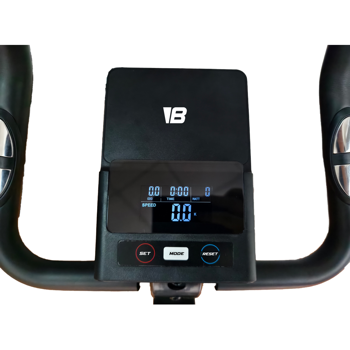Consola negra de bicicleta estática con pantalla digital que muestra 0.0 para velocidad, tiempo y vatios. Botones de ajuste, modo y reinicio visibles.