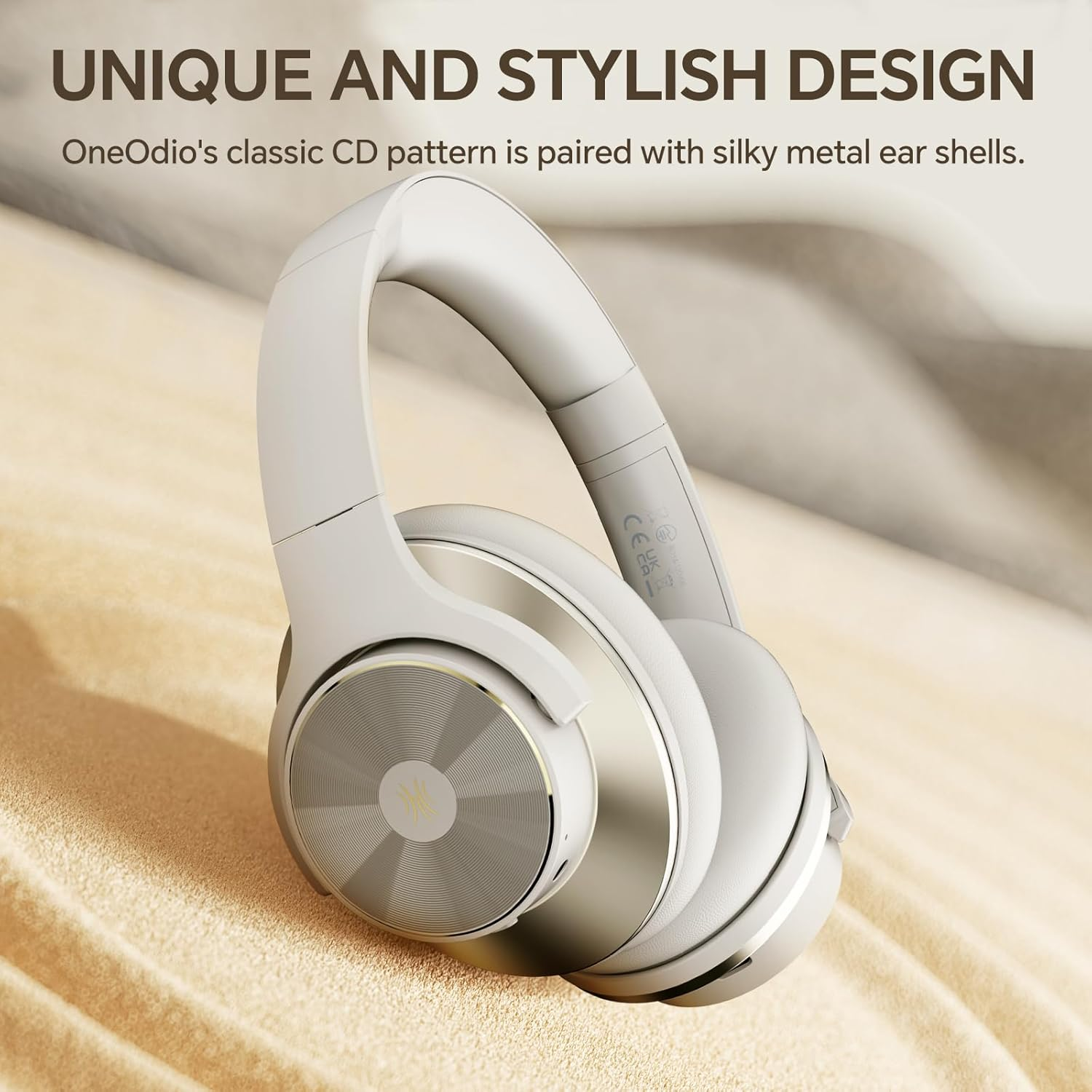 Weiße und silberne Kopfhörer mit kreisförmigem Design, die auf einer sandigen Oberfläche liegen. Der Text lautet 'UNIQUE AND STYLISH DESIGN'.