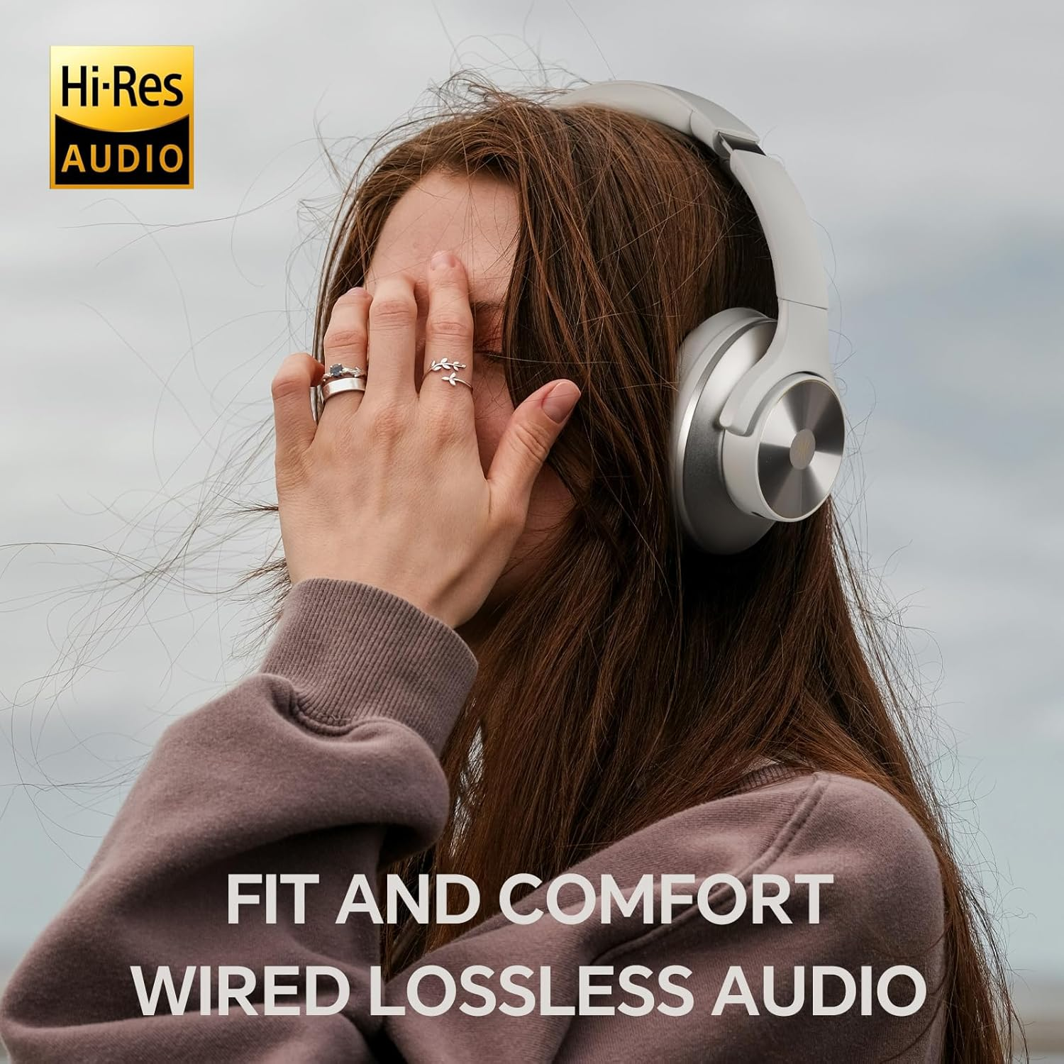 Eine Frau trägt Kopfhörer. Sie trägt Ringe. Der Text lautet 'FIT AND COMFORT WIRED LOSSLESS AUDIO'. Ein 'Hi-Res AUDIO'-Logo ist sichtbar.