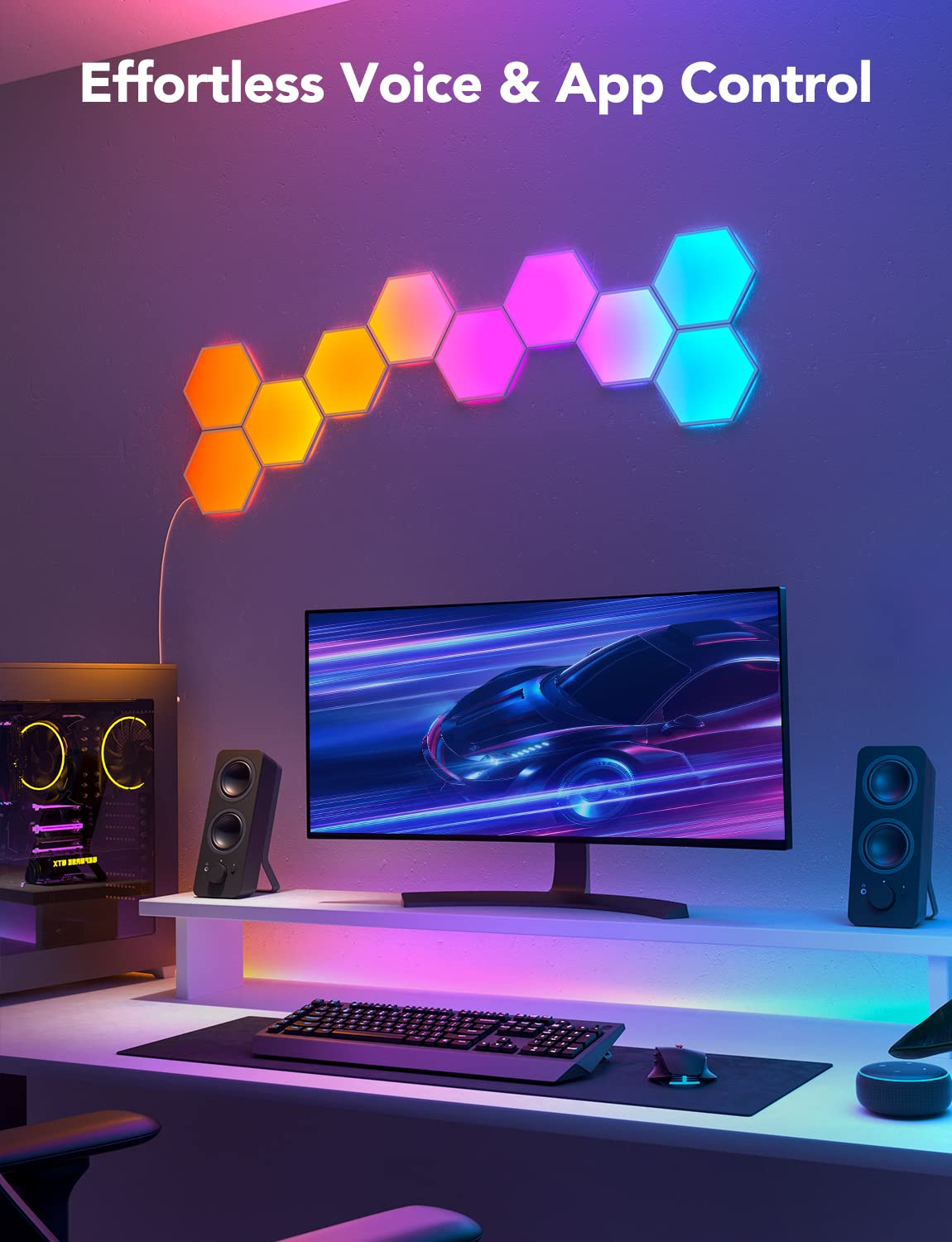 Un'impostazione di gioco con monitor, tastiera, altoparlanti e luci esagonali. Il muro è viola, con luci di vari colori.