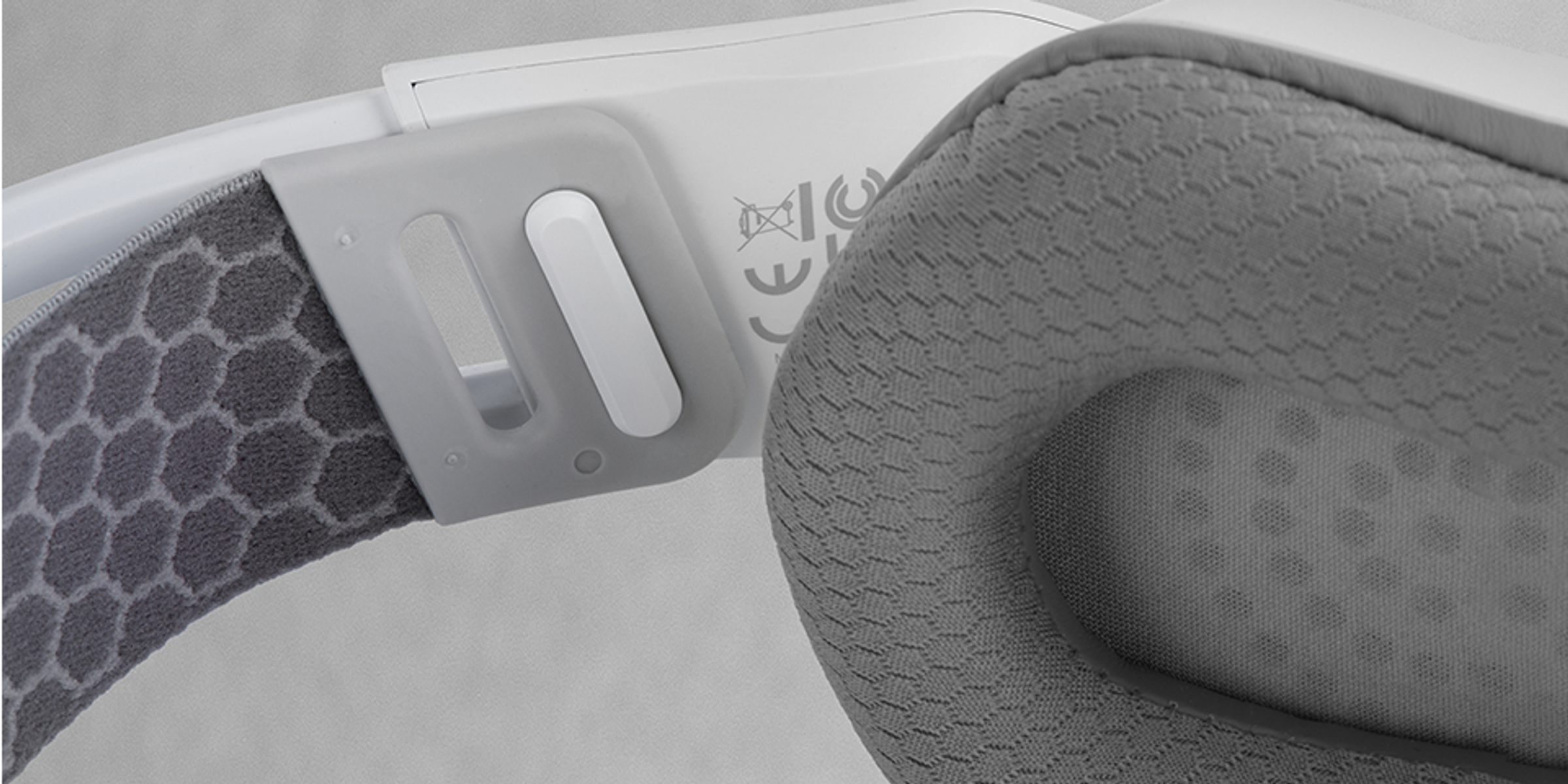 Zbliżenie białego i szarego zestawu słuchawkowego. Nauszniki i pałąk są szare. Widoczna jest część białej ramy.