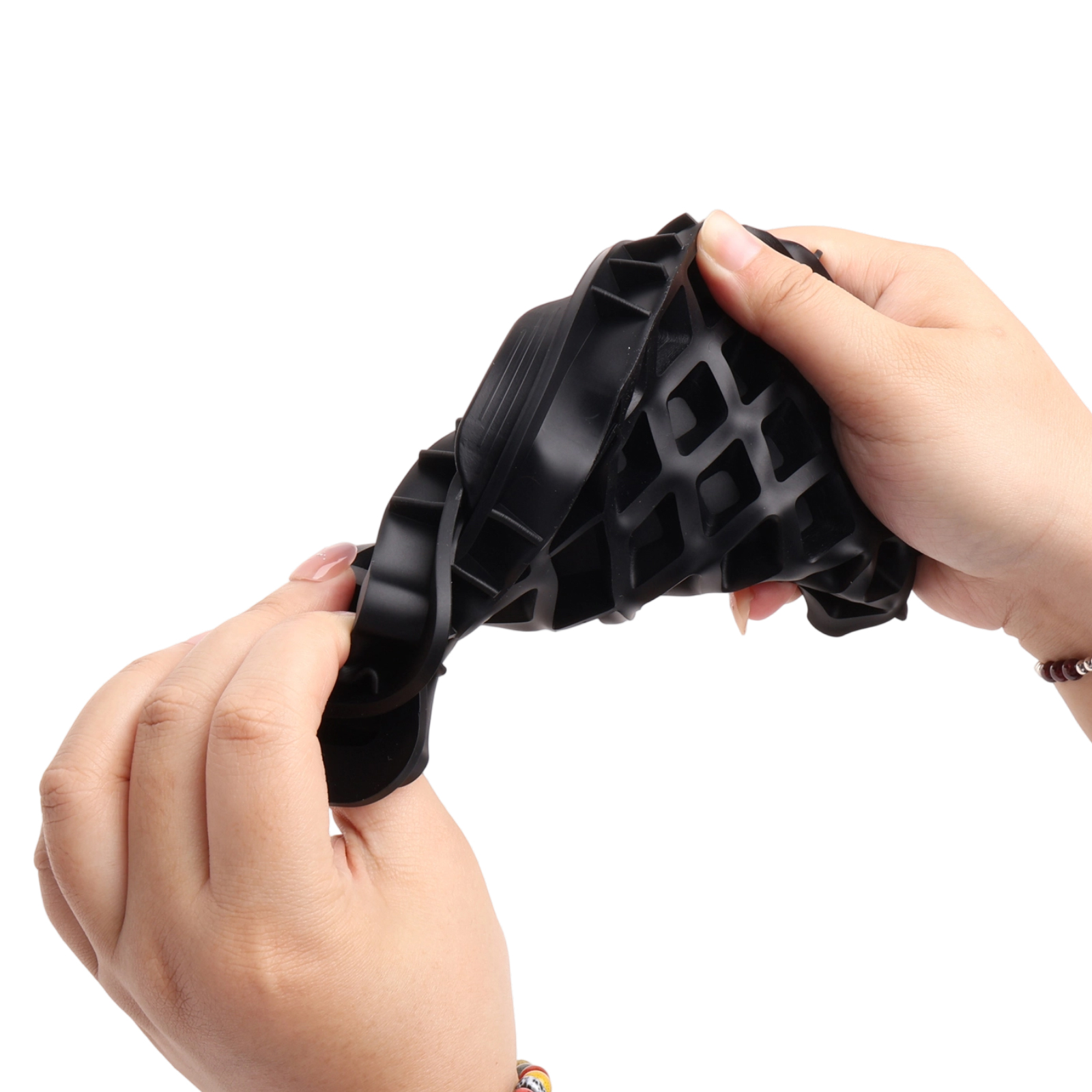 Hände halten ein schwarzes, flexibles Objekt mit geometrischem Muster vor weißem Hintergrund.
