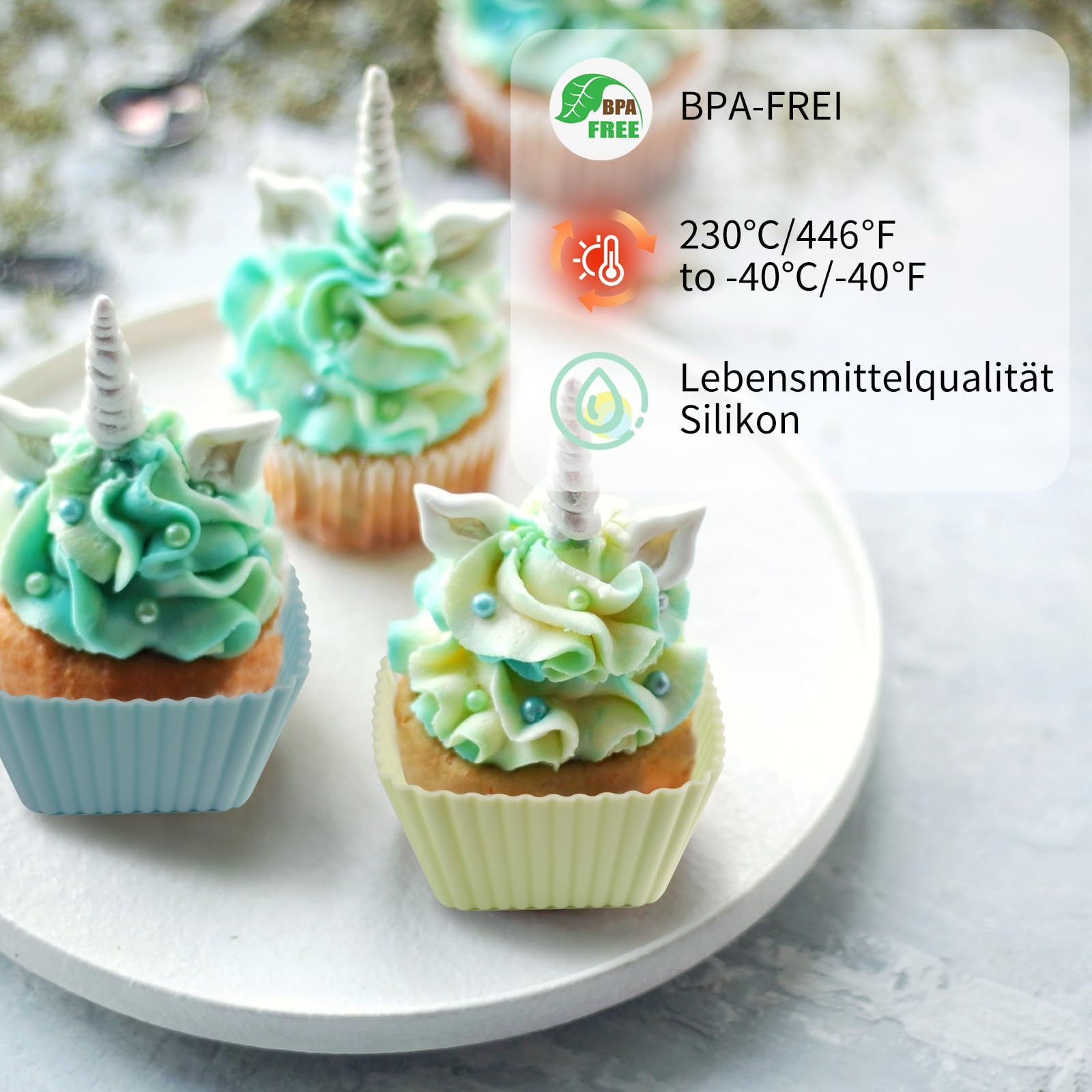 Drei Einhorn-Cupcakes mit blauem und grünem Zuckerguss auf einem weißen Teller. Text-Overlays zeigen BPA-frei und Temperaturbeständigkeit an.