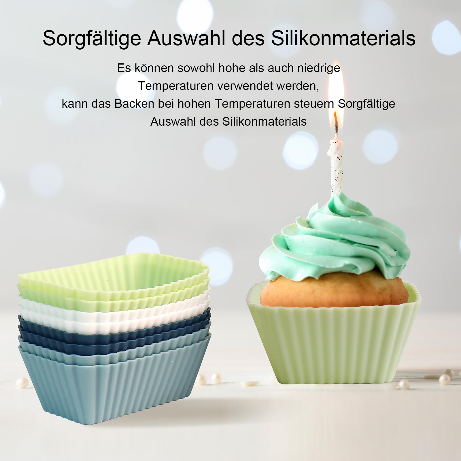 Ein Cupcake mit grüner Glasur und einer brennenden Kerze, neben Stapeln farbiger Silikon-Backformen.