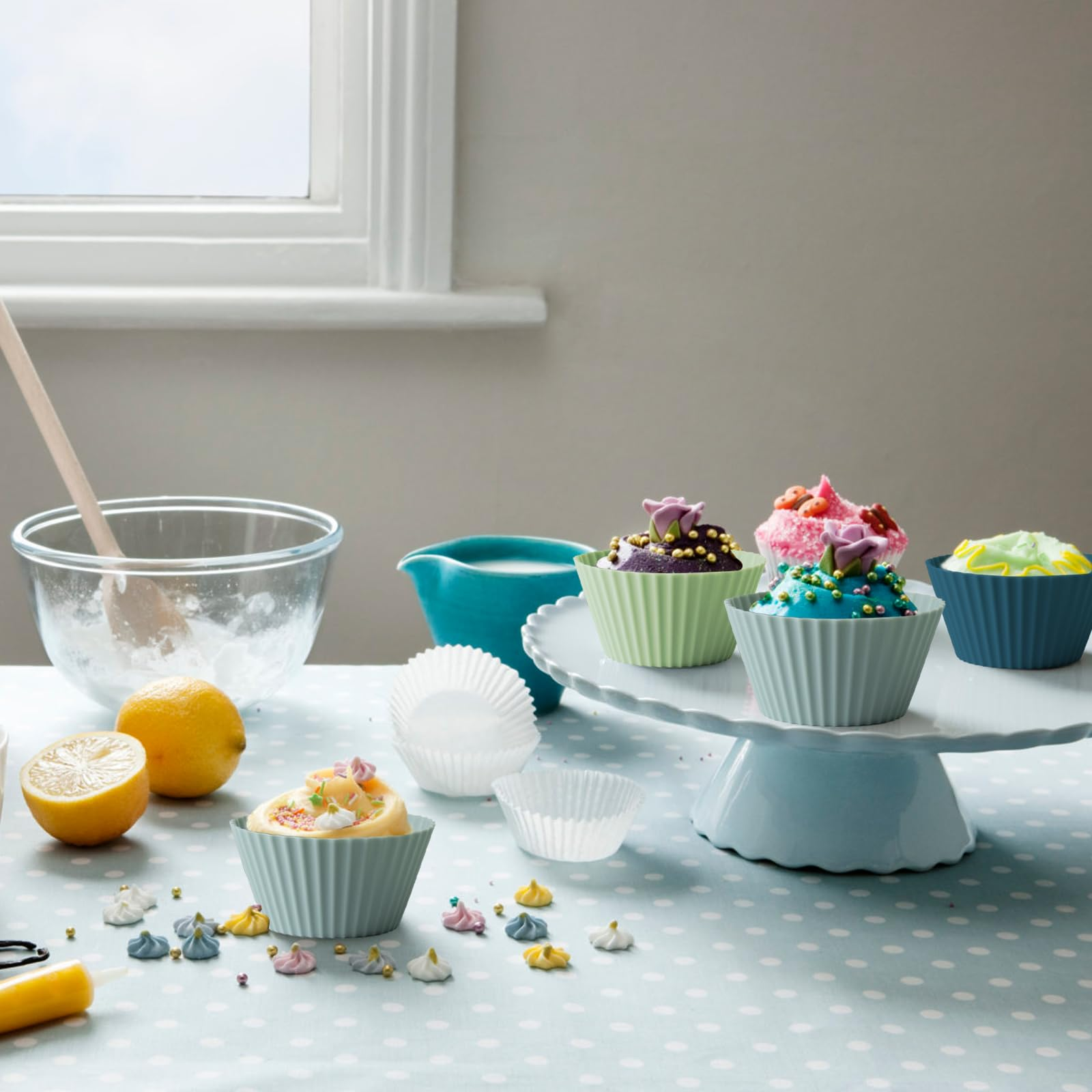 Cupcakes auf einem Tisch mit Zitronen, Schüsseln und Dekorationen. Blaues Tischtuch mit Punkten.