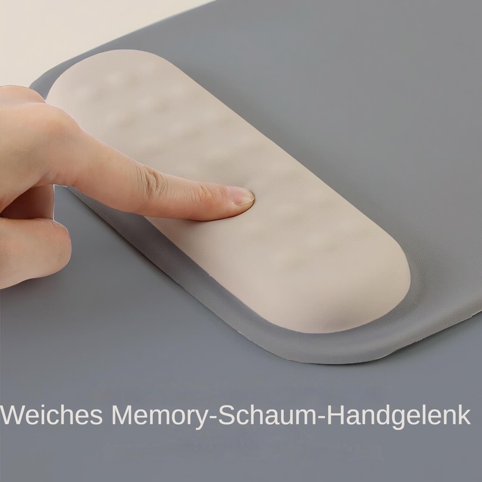 Eine Hand drückt eine beige Handgelenkauflage auf eine graue Oberfläche. Die Auflage ist für eine Tastatur.
