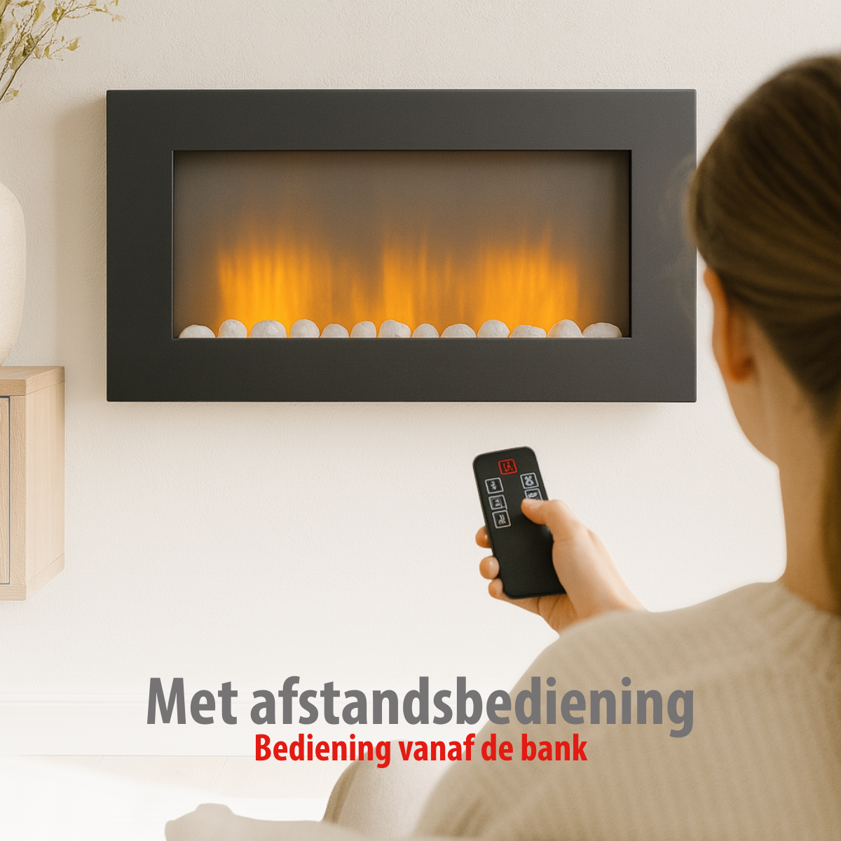 Een vrouw bedient een haard met een afstandsbediening. De haard is zwart, met witte stenen en oranje vlammen.