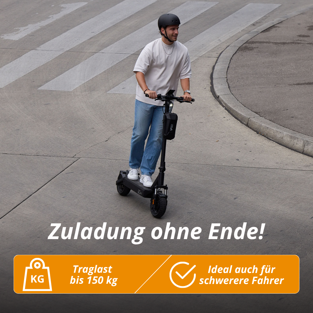 Ein Mann fährt mit einem E-Scooter auf einer Straße. Er trägt einen Helm, Jeans und ein weißes Hemd. Der Roller ist schwarz.