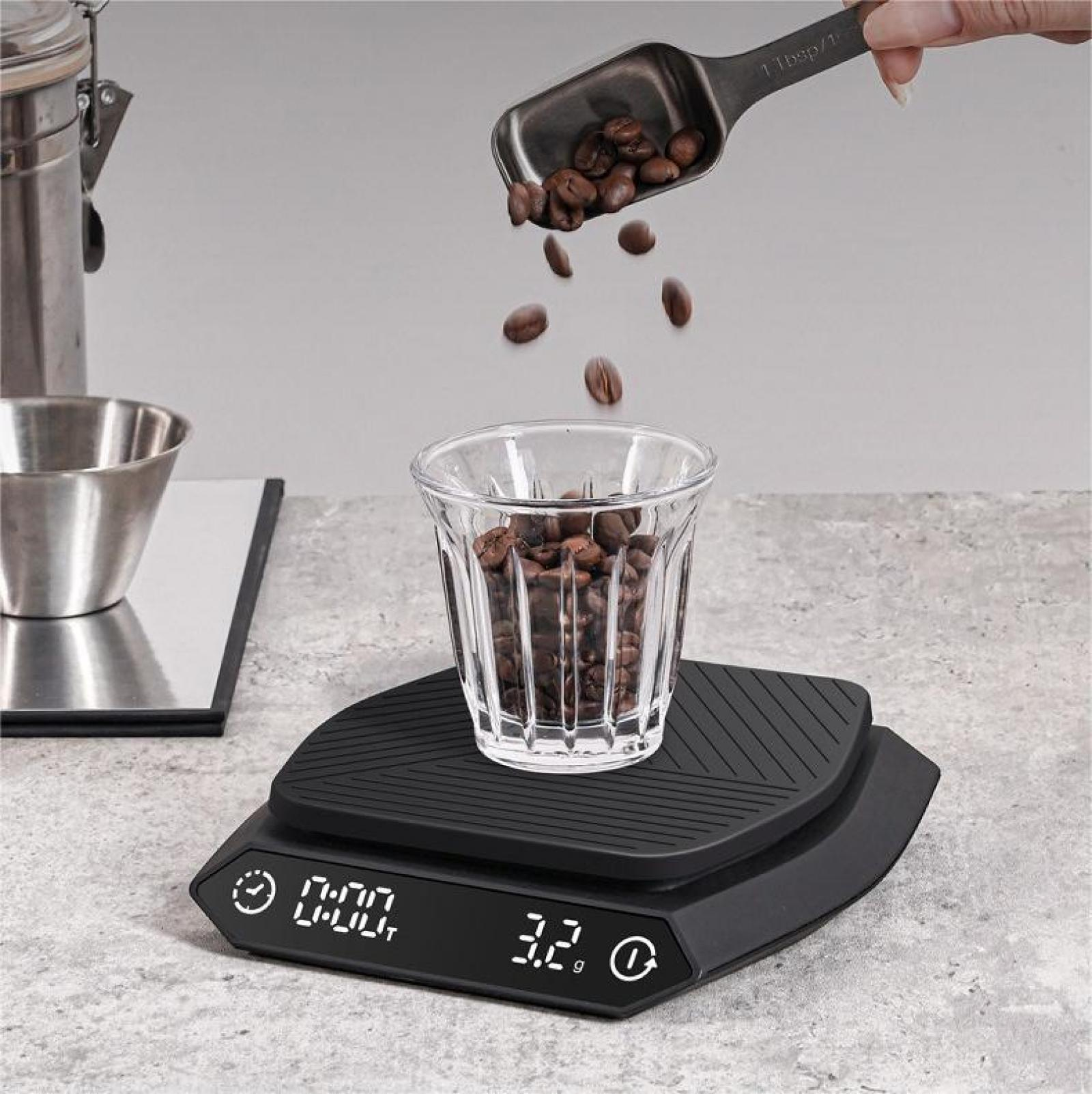 Kaffeebohnen werden aus einem Löffel in ein Glas auf einer Waage gegossen. Zeit und Gewicht werden angezeigt.