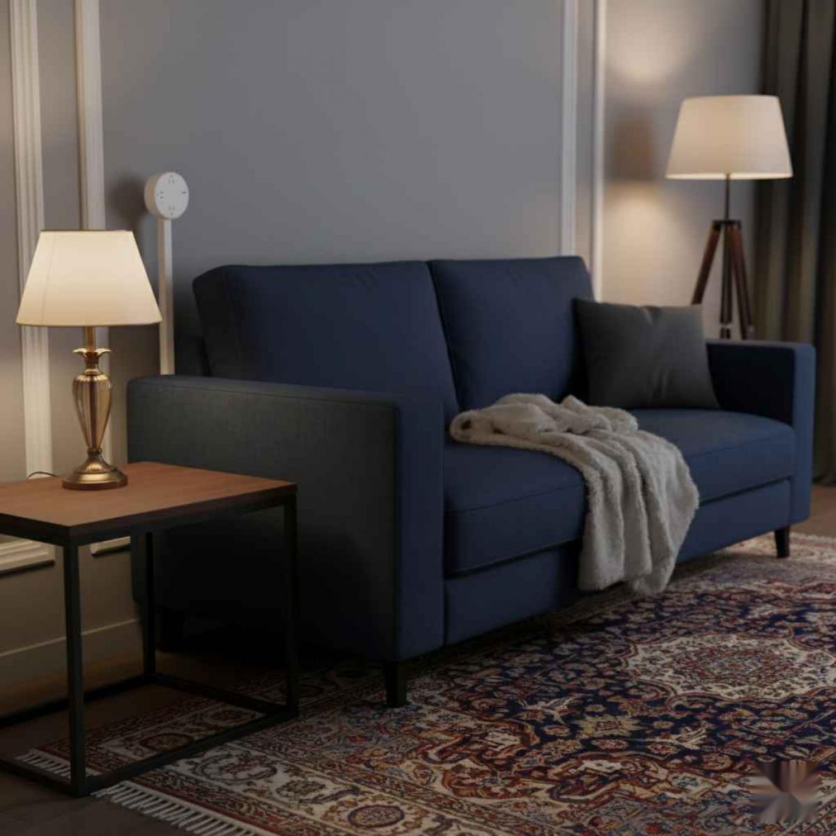 Ein Raum mit blauem Sofa, Lampe, Beistelltisch, Teppich und Stehlampe. Auf dem Sofa liegt eine Decke und ein Kissen.
