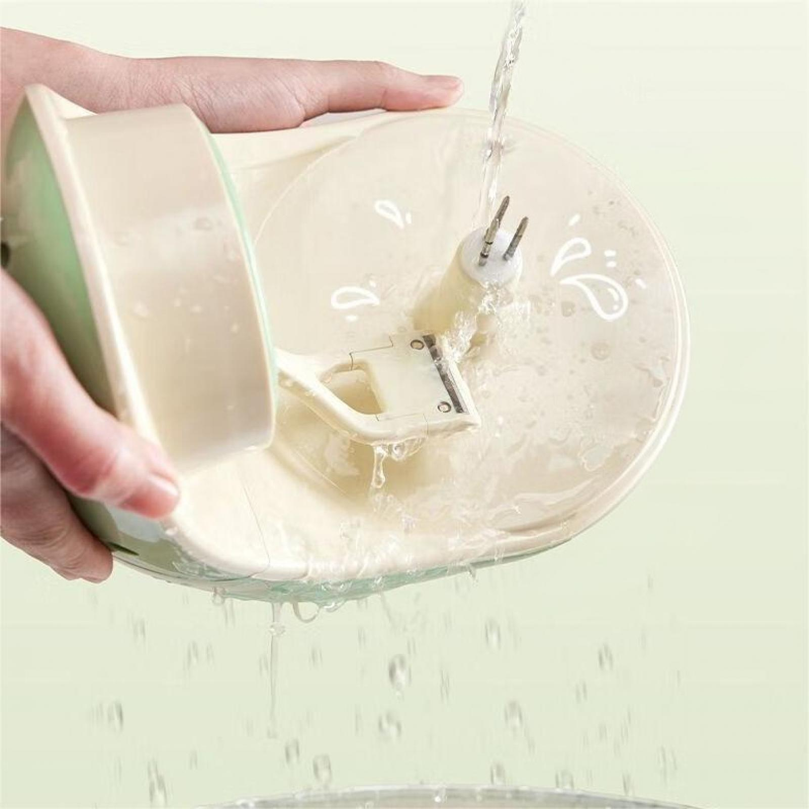 Wasser gießt auf ein weißes Küchengerät. Eine Hand hält das Gerät. Der Hintergrund ist ein sanftes Grün.