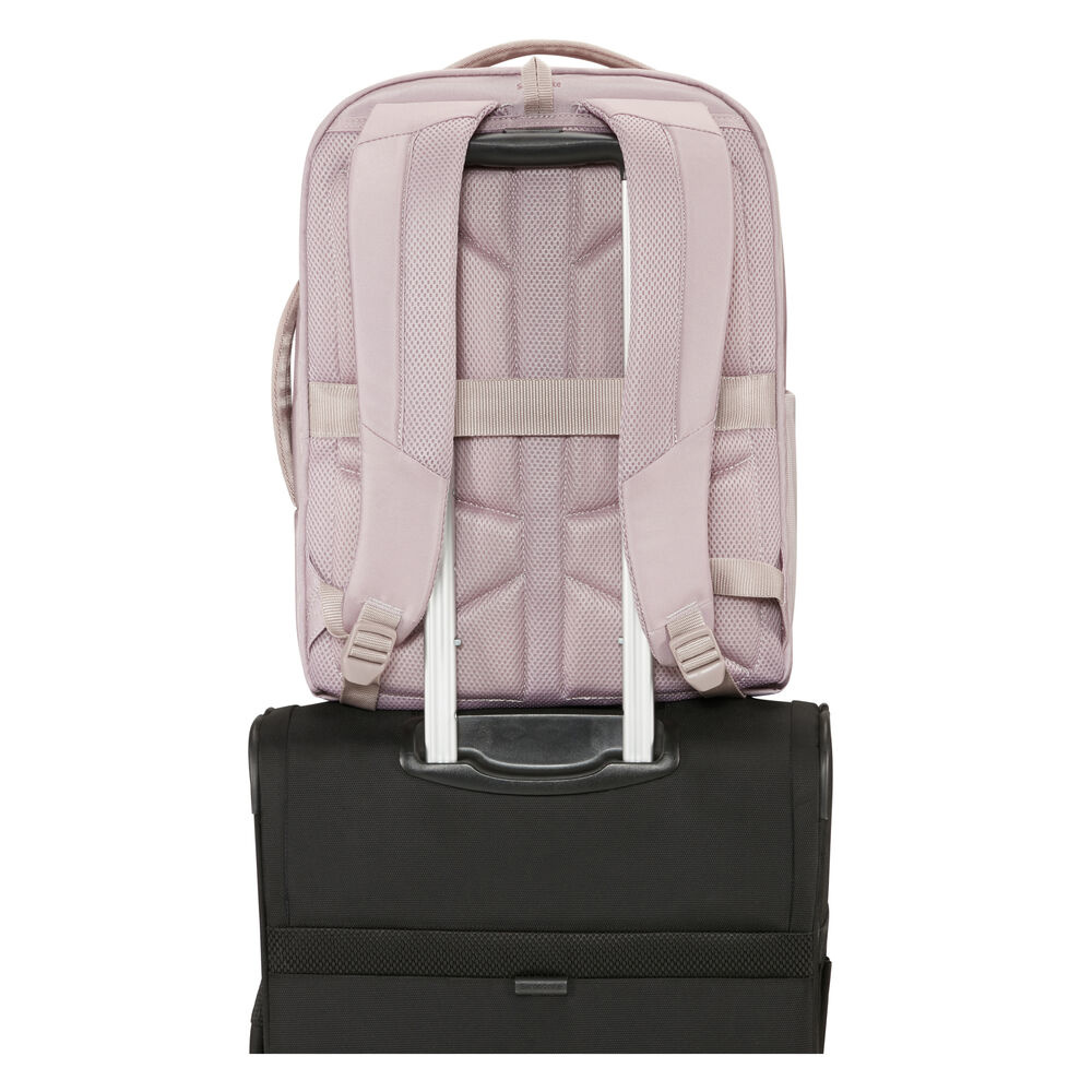 Ein malvenfarbener Rucksack liegt auf einem schwarzen Koffer. Der Rucksack hat Schultergurte. Der Koffer hat einen Griff und silberne Stangen.