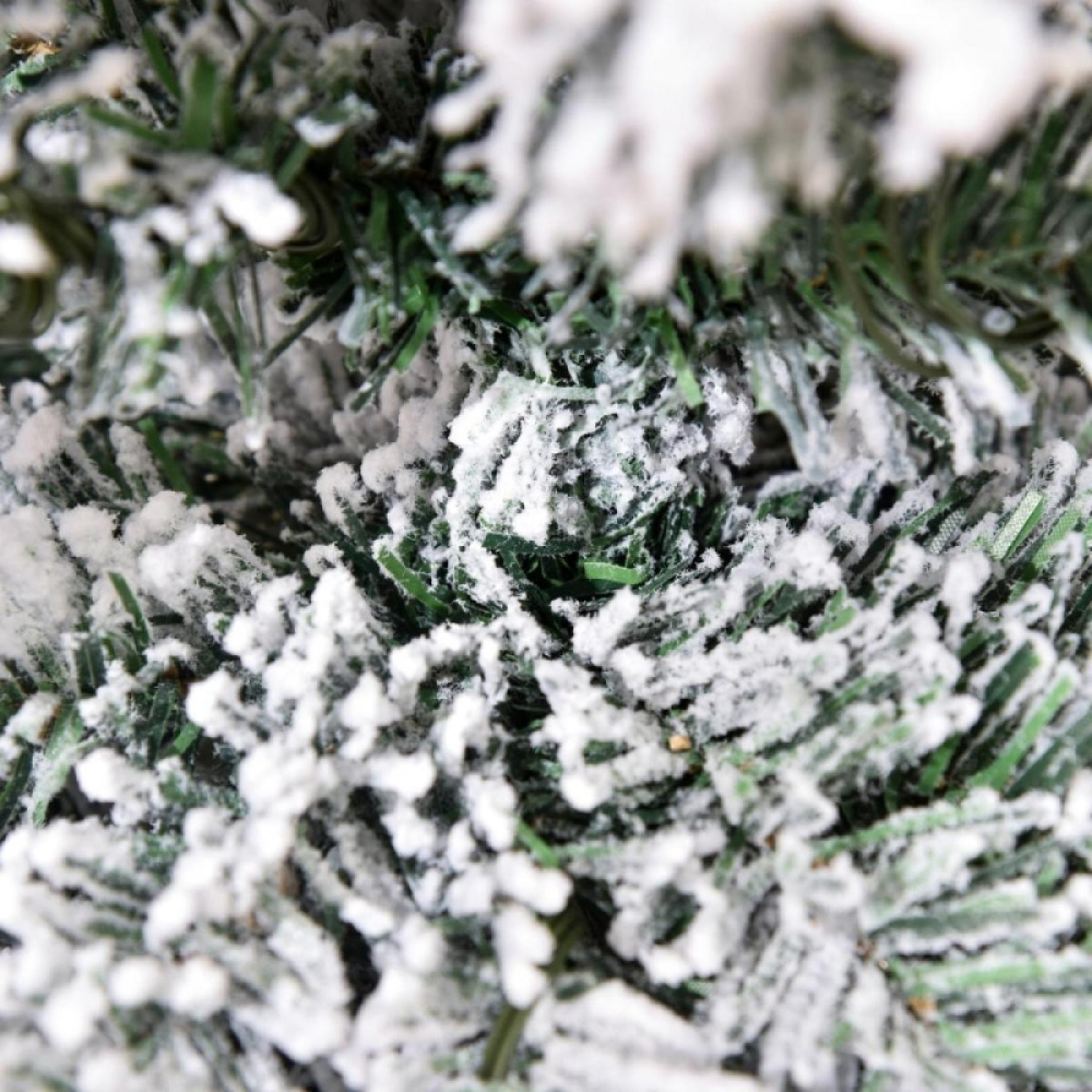 Nahaufnahme eines schneebedeckten Nadelbaums. Grüne Nadeln sind mit Weiß bedeckt, was eine Winterlandschaft erzeugt.