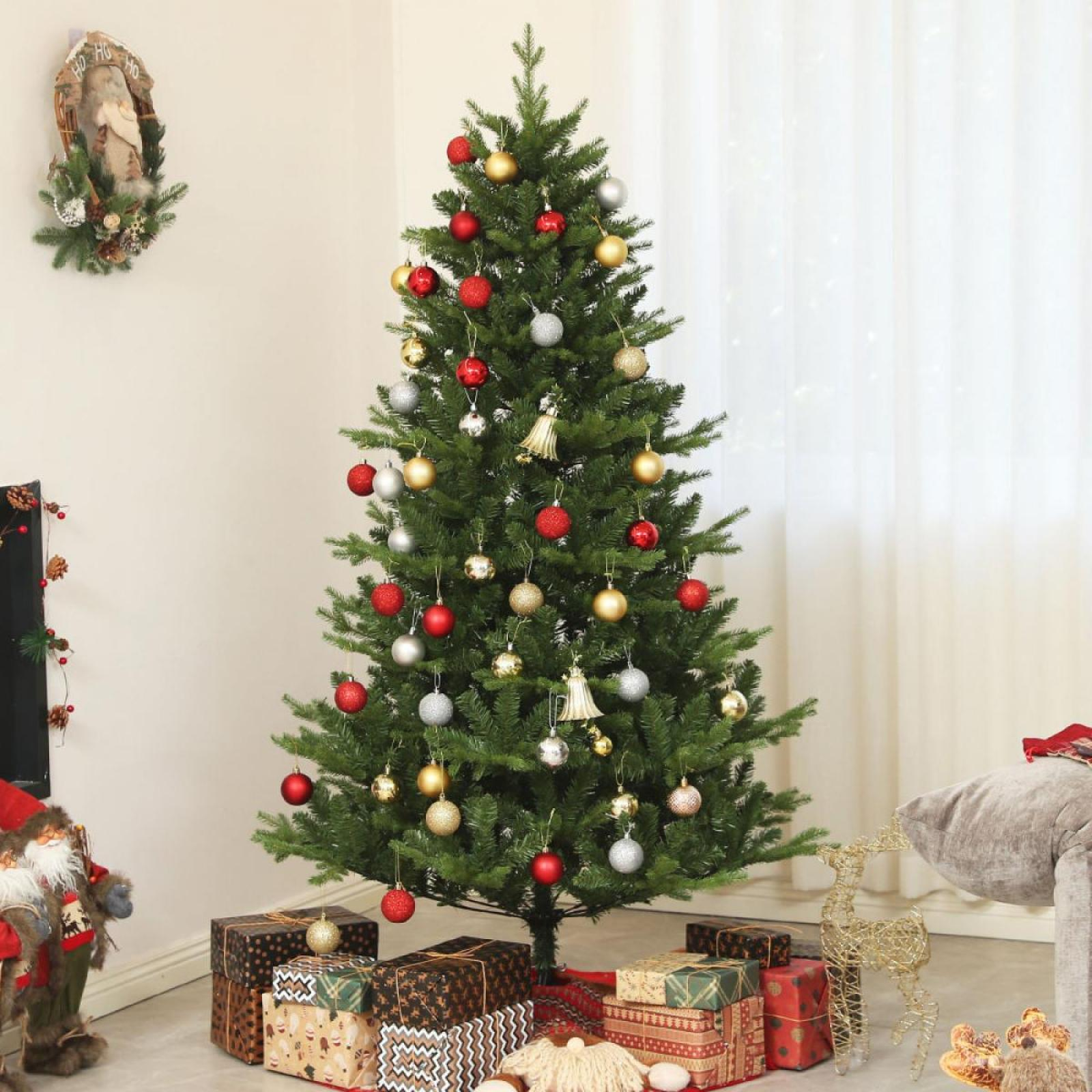 Ein geschmückter Weihnachtsbaum mit roten, goldenen und silbernen Ornamenten, umgeben von Geschenkpapier, einem Kranz und einer Rentierdekoration.