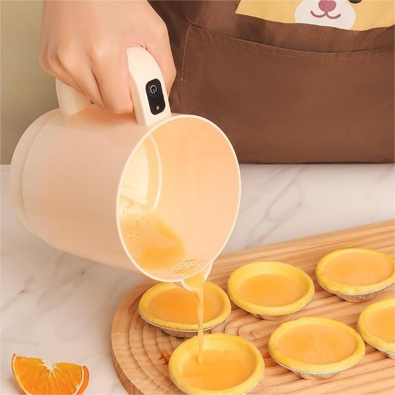Eine Hand gießt orangefarbene Flüssigkeit aus einem Krug in kleine Törtchen auf einem Holzbrett. Auf der linken Seite ist eine Orangenscheibe.