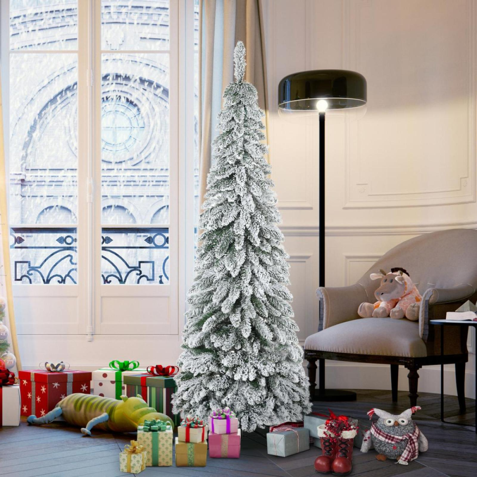 Ein geschmückter Weihnachtsbaum steht in der Nähe eines Fensters. Geschenke und Spielzeug befinden sich an seiner Basis. Rechts sind ein Stuhl und eine Lampe.