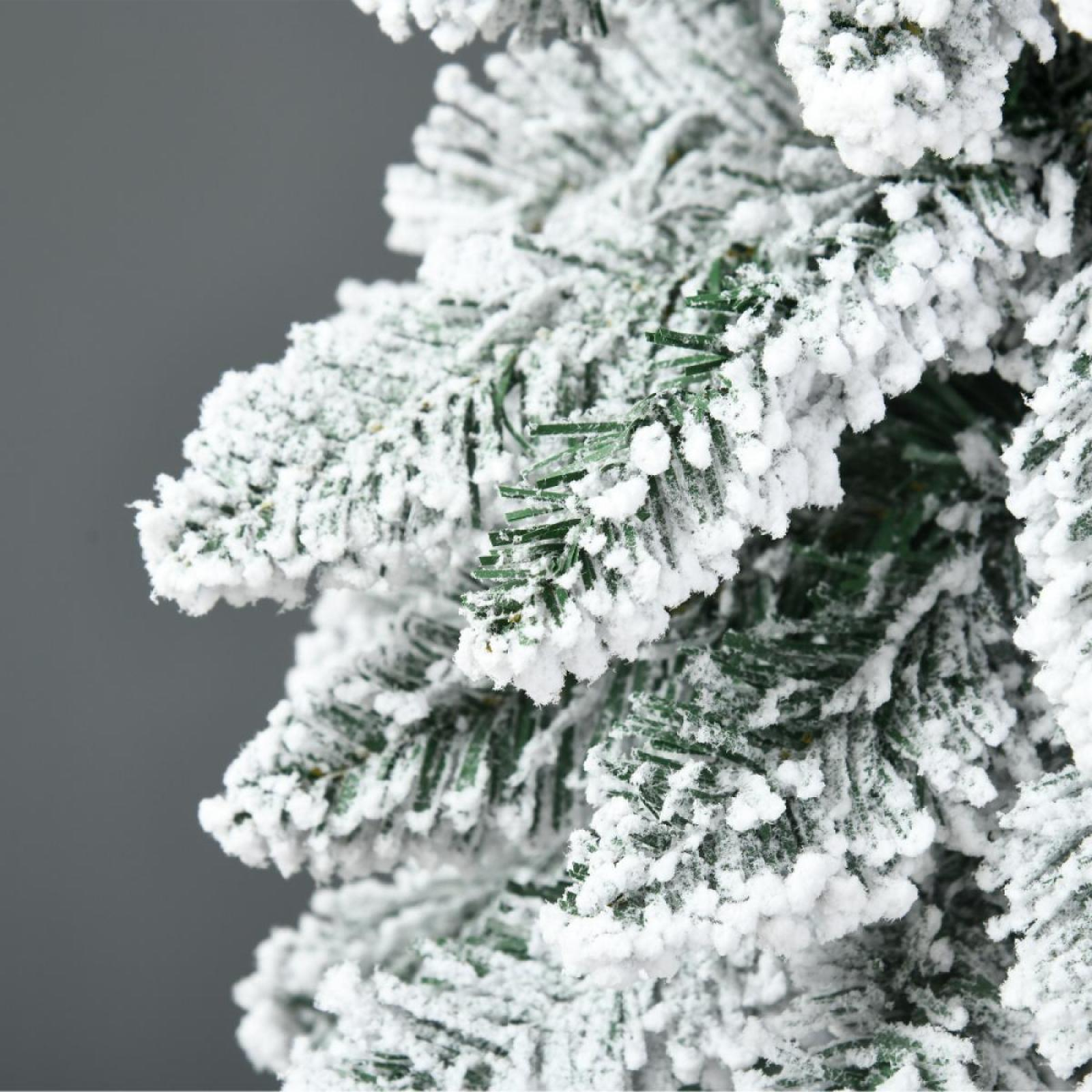 Nahaufnahme eines schneebedeckten Weihnachtsbaumzweigs mit grünen Nadeln und weißem Schnee vor grauem Hintergrund.