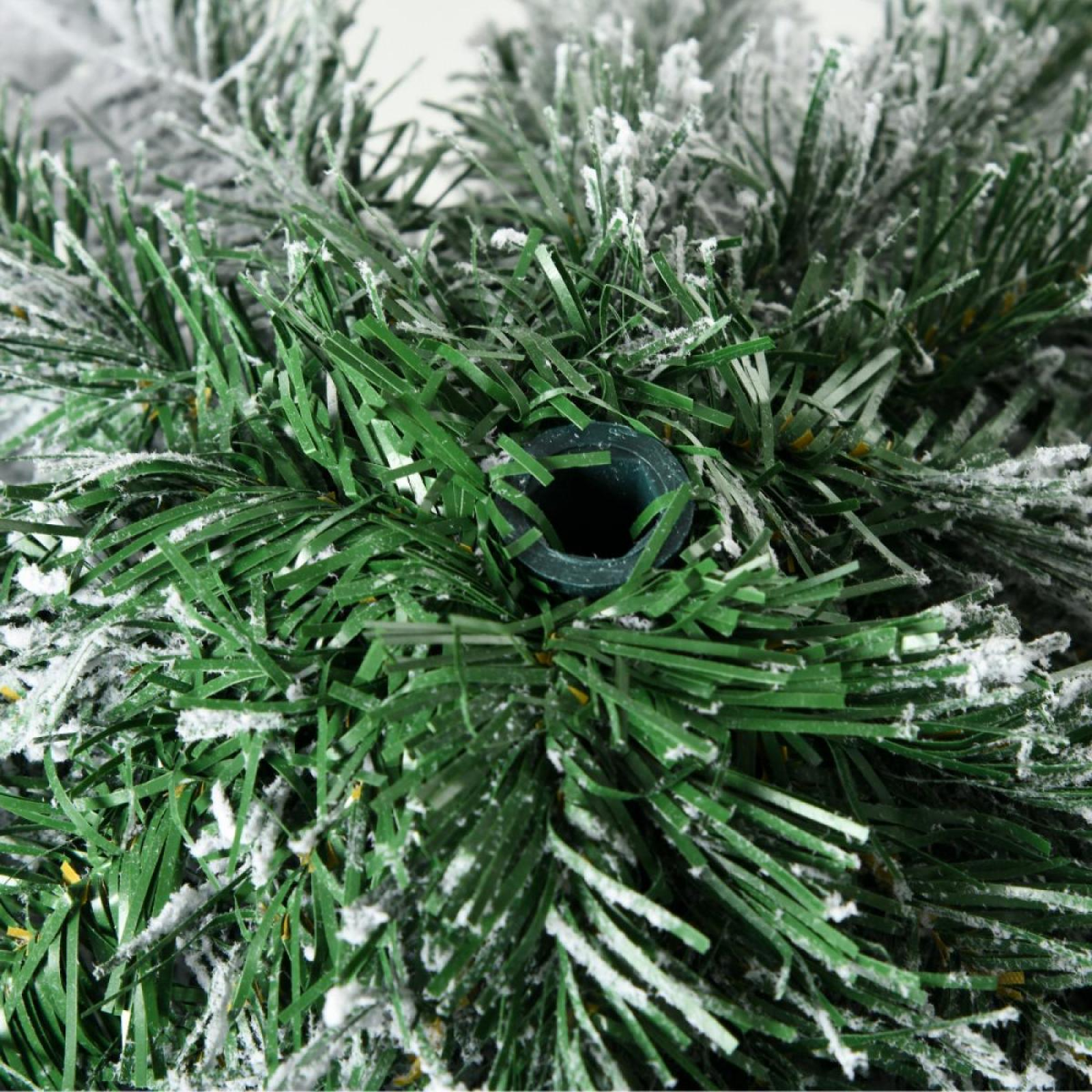 Nahaufnahme eines grünen künstlichen Weihnachtsbaumzweigs mit weißem, schneegleichem Belag und einem dunkelgrünen Loch in der Mitte.