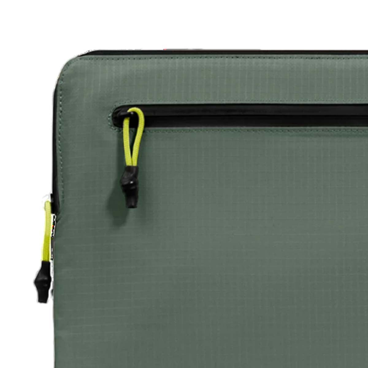 Primo piano di un angolo di borsa verde. Presenta una cerniera nera, tiranti gialli e una trama a griglia sulla superficie.