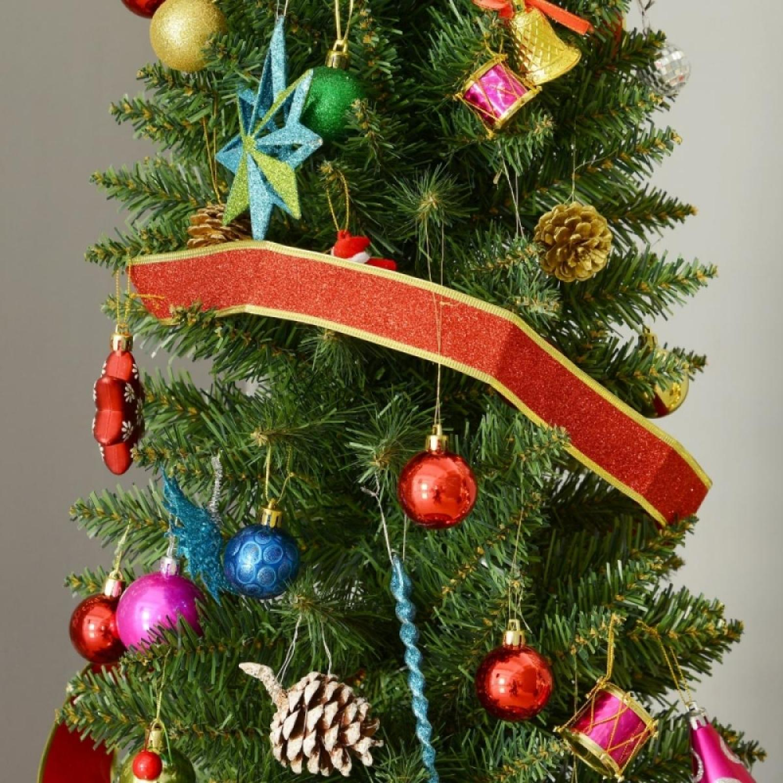 Ein geschmückter Weihnachtsbaum mit Ornamenten in verschiedenen Farben, darunter Rot, Gold, Blau und Rosa, und einem roten Band.