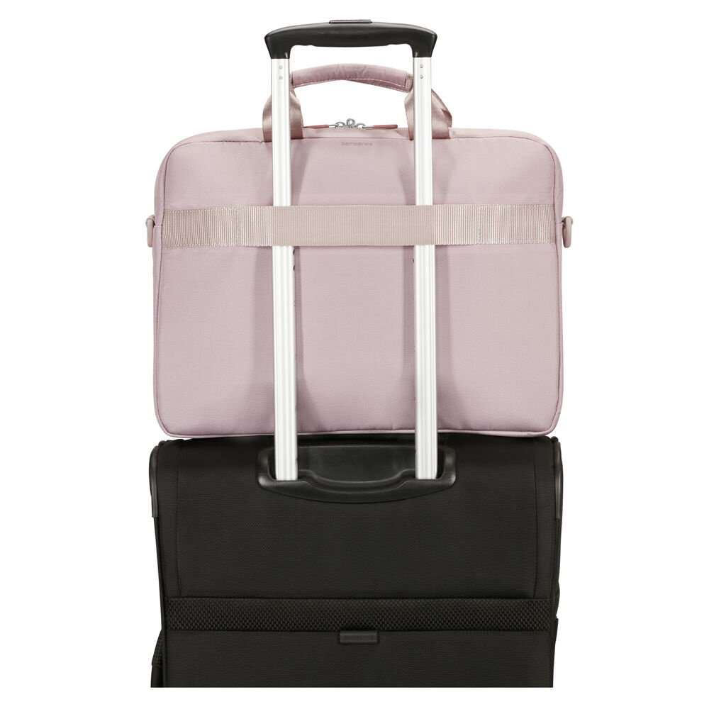 Eine rosa Laptoptasche liegt auf einem schwarzen Koffer. Silberner Griff und Riemen sichern die Tasche. Isoliert auf weißem Hintergrund.