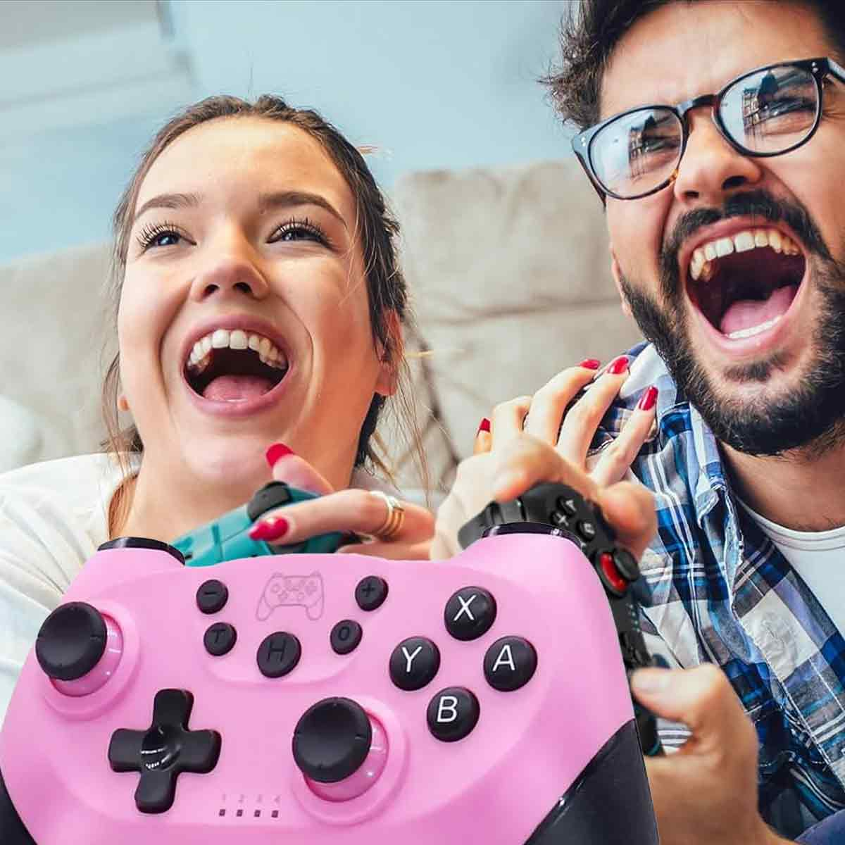 Ein Mann und eine Frau lachen und halten einen rosa Videospiel-Controller. Sie sind in einem Wohnzimmer.