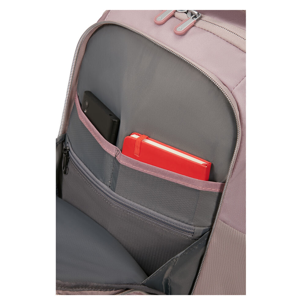 Nahaufnahme des Rucksackinneren. Ein rotes Notizbuch und ein schwarzes Telefon befinden sich in den Taschen. Der Rucksack ist staubrosa.