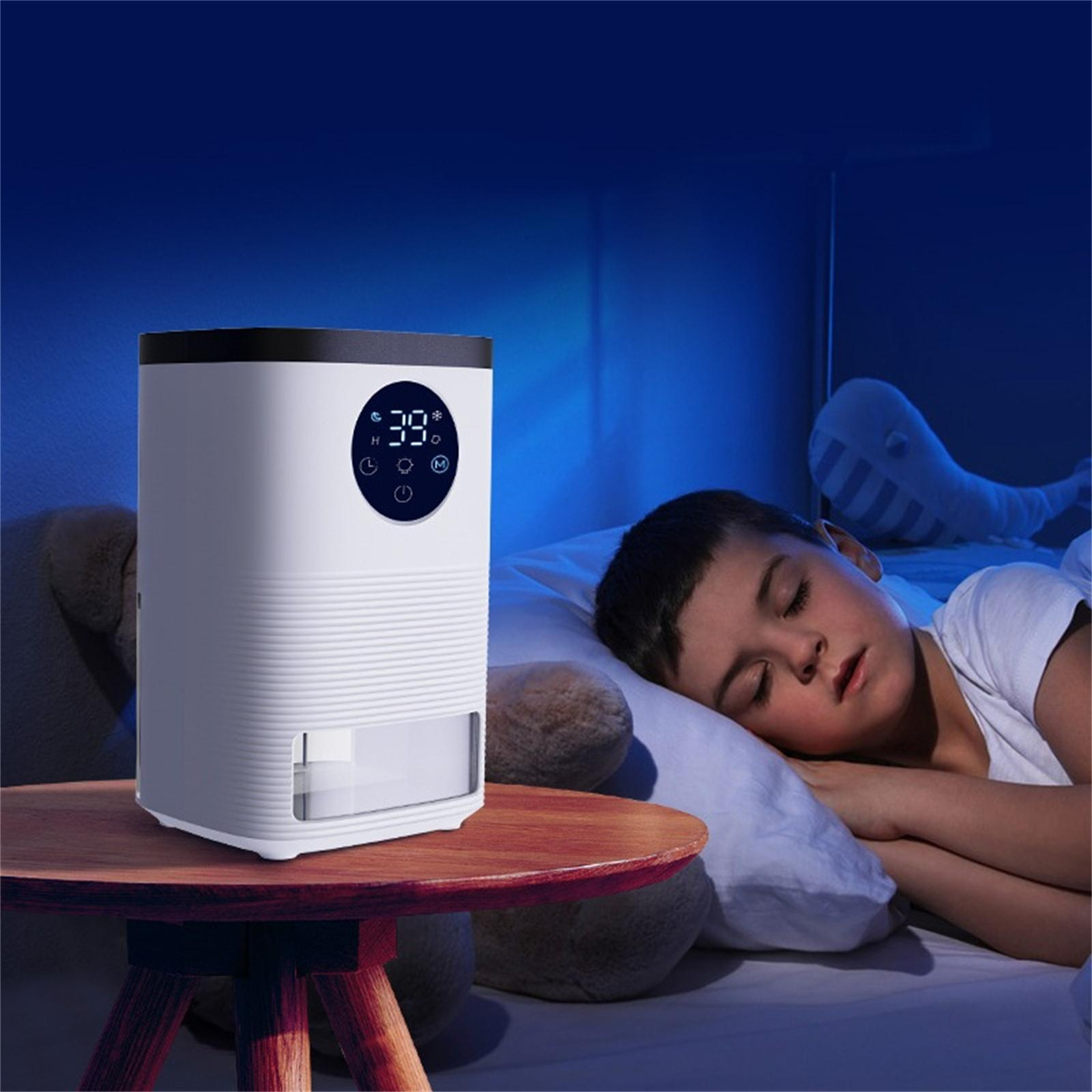 Ein Junge schläft im Bett, ein weißer Luftbefeuchter steht auf einem Tisch. Der Luftbefeuchter zeigt 39 Grad. Ein Stoffwal ist im Hintergrund.