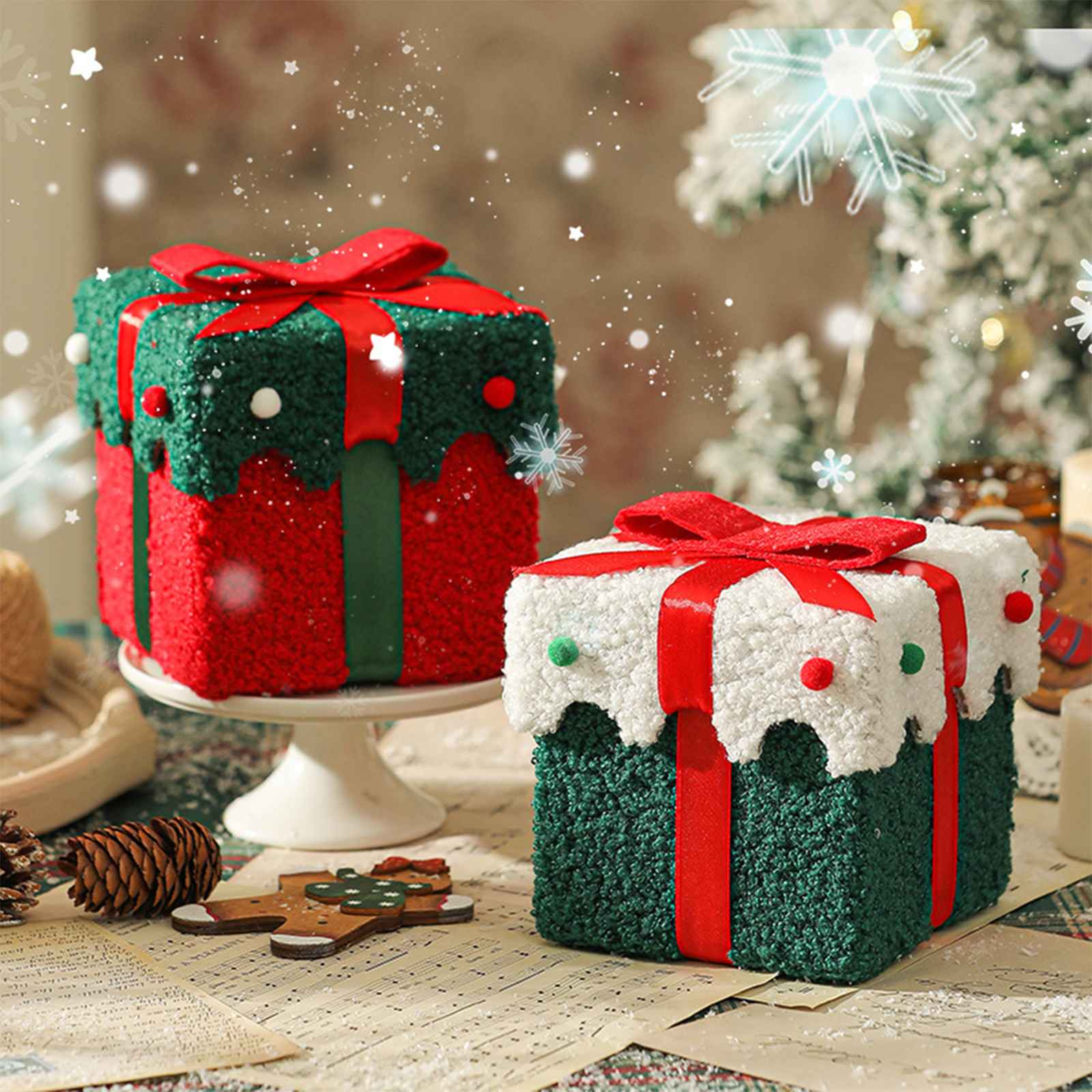 Zwei dekorative Geschenkboxen mit roten und grünen Farben, roten Bändern, Schneeflocken und festlichen Dekorationen auf einem Tisch.