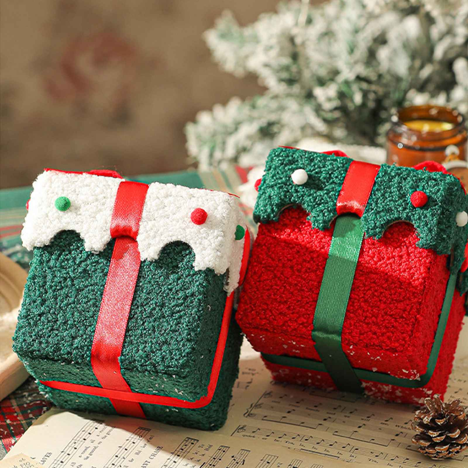 Zwei dekorative Weihnachtsgeschenke. Eines grün und eines rot, beide mit Schleife und weißen Akzenten, auf Notenblättern.