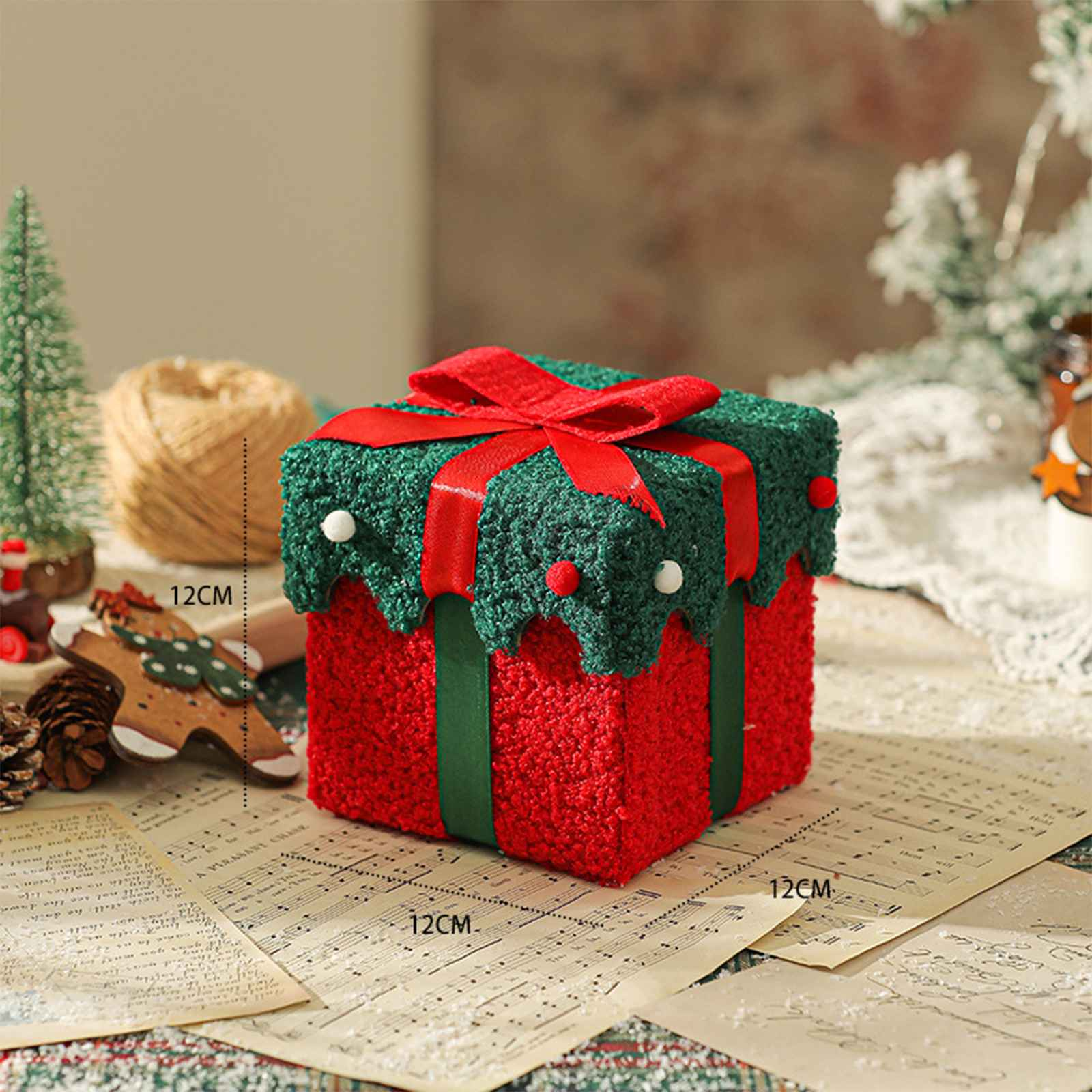 Eine rot-grüne Weihnachtsgeschenkbox mit Schleife, verziert mit weißen Perlen, auf Notenblättern.