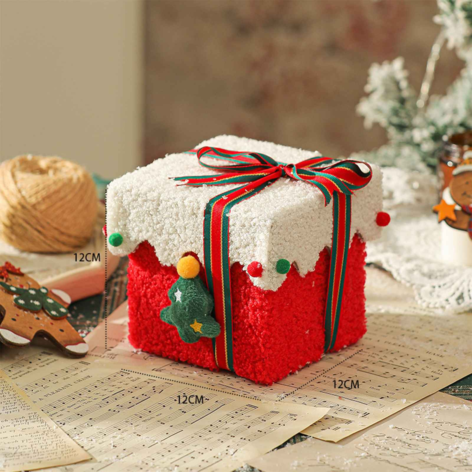Eine dekorative Weihnachtsgeschenkbox mit rotem und weißem Fell. Sie hat ein Band und eine Weihnachtsbaumdekoration.