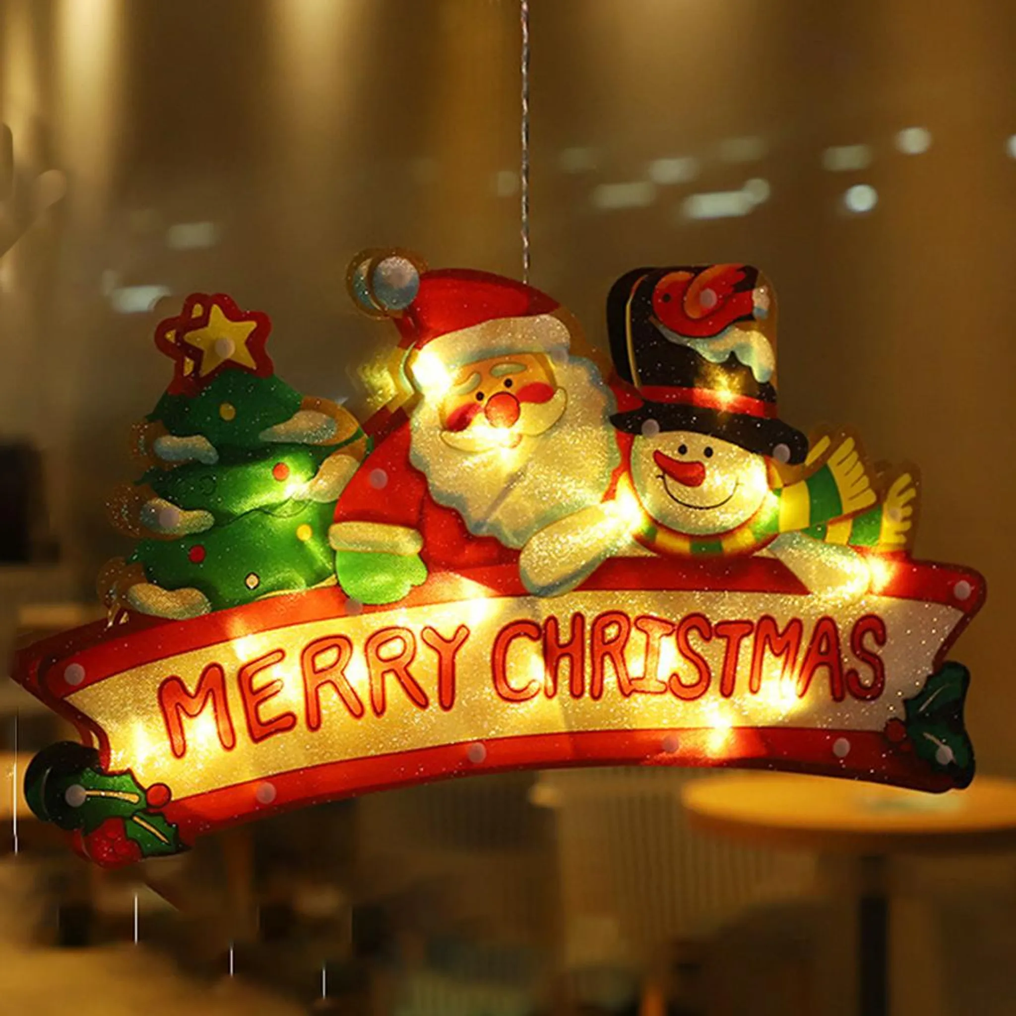Weihnachtsdekoration mit Weihnachtsmann, Schneemann und Baum, mit "Frohe Weihnachten" Text, beleuchtet und hängend.