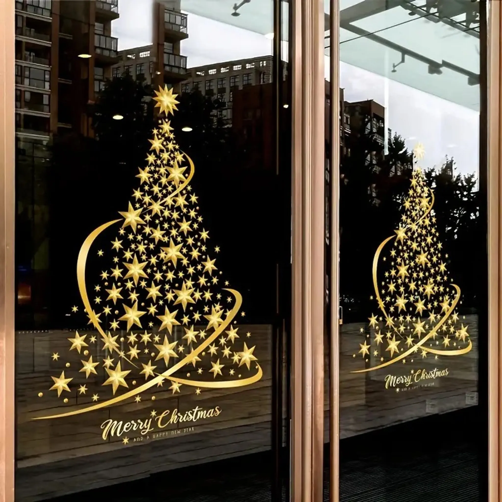 Goldene Sterne Weihnachtsbaum auf Glastür. Frohe Weihnachten Text unten. Hintergrund zeigt Gebäude und Himmel.