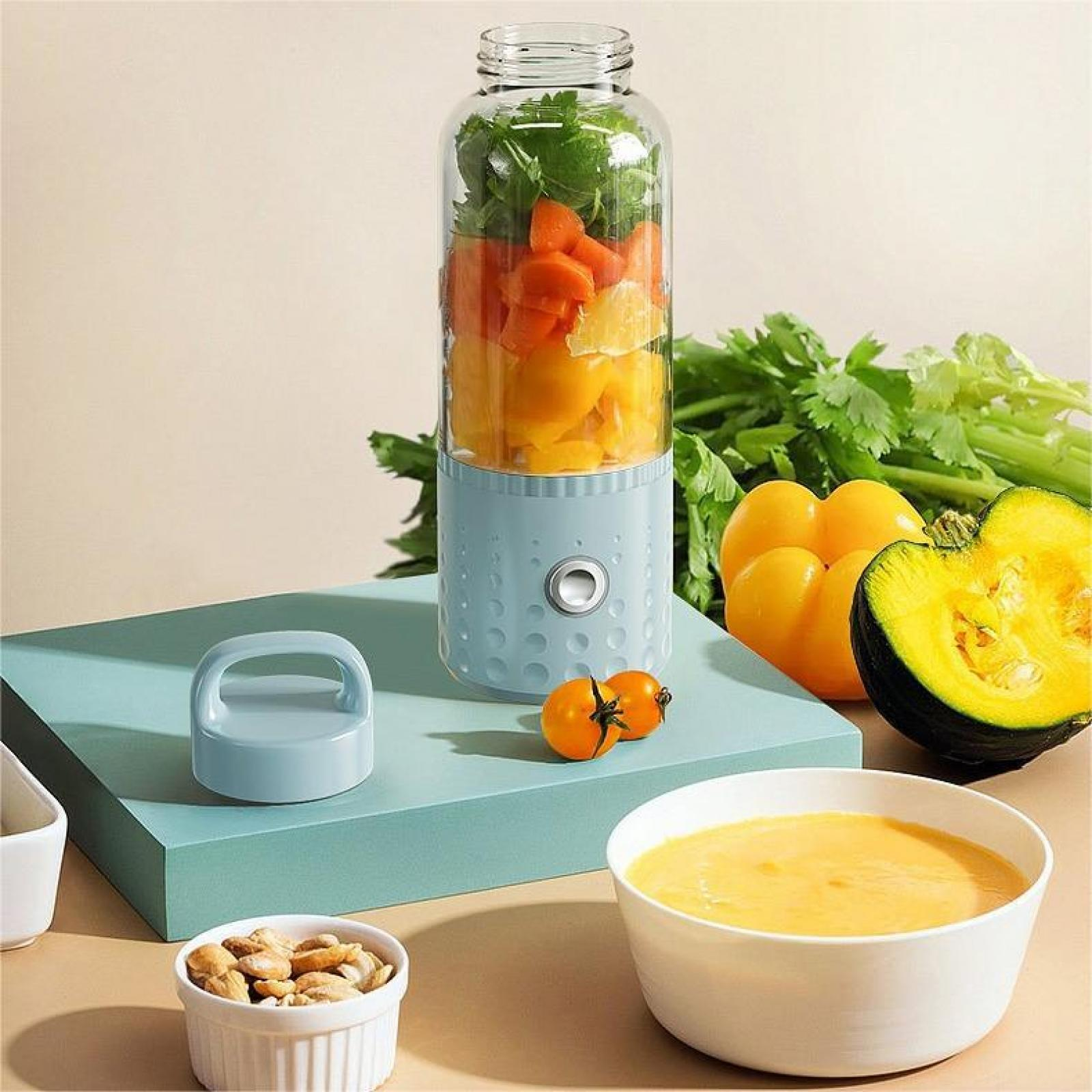 Mixer mit Gemüse. Daneben Tomaten, eine Schüssel Suppe, Nüsse und Kürbis. Blauer Platz.
