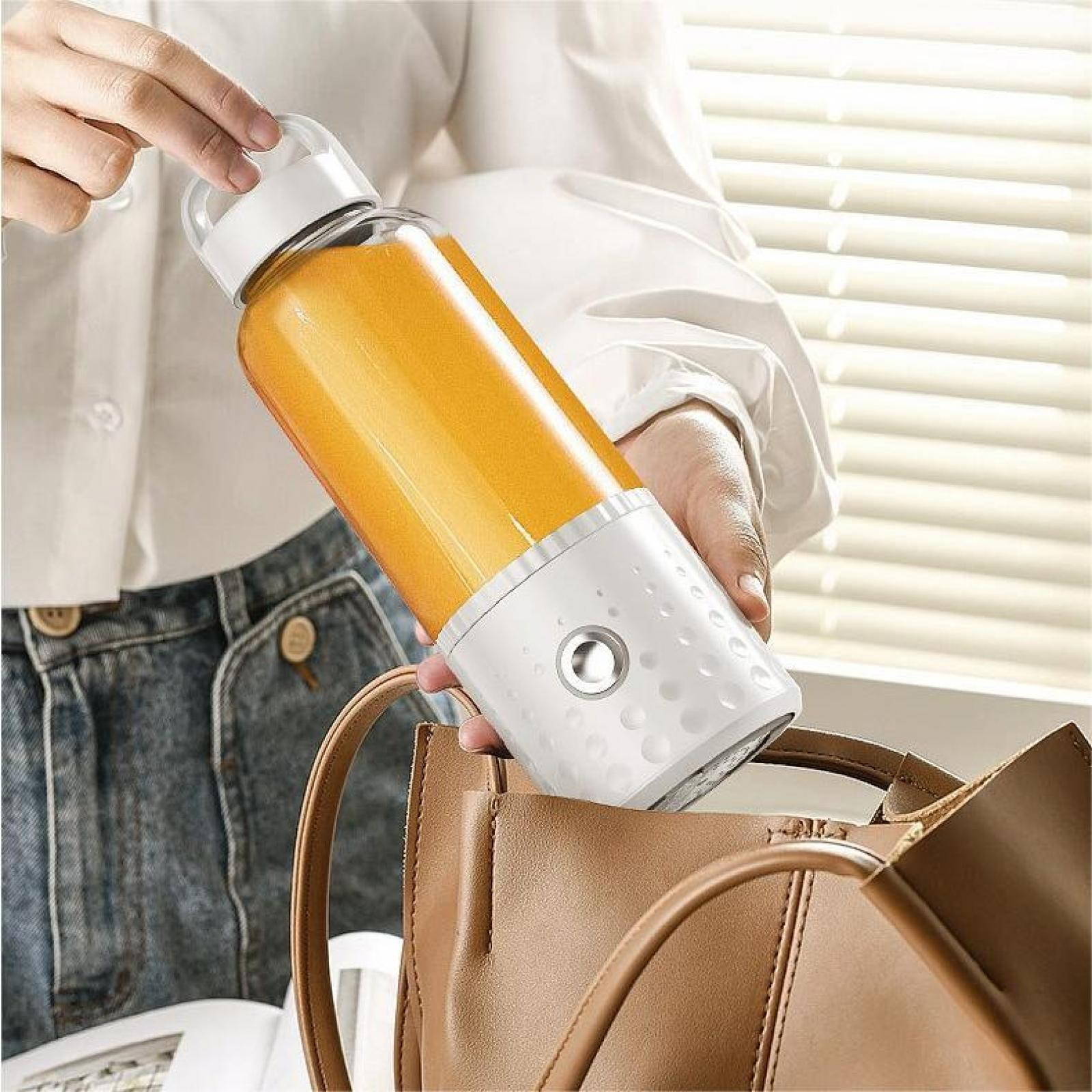 Eine Person hält eine Saftflasche mit weißem Sockel und orangener Flüssigkeit über einer braunen Tasche. Hintergrund: weißes Hemd und Jeans.
