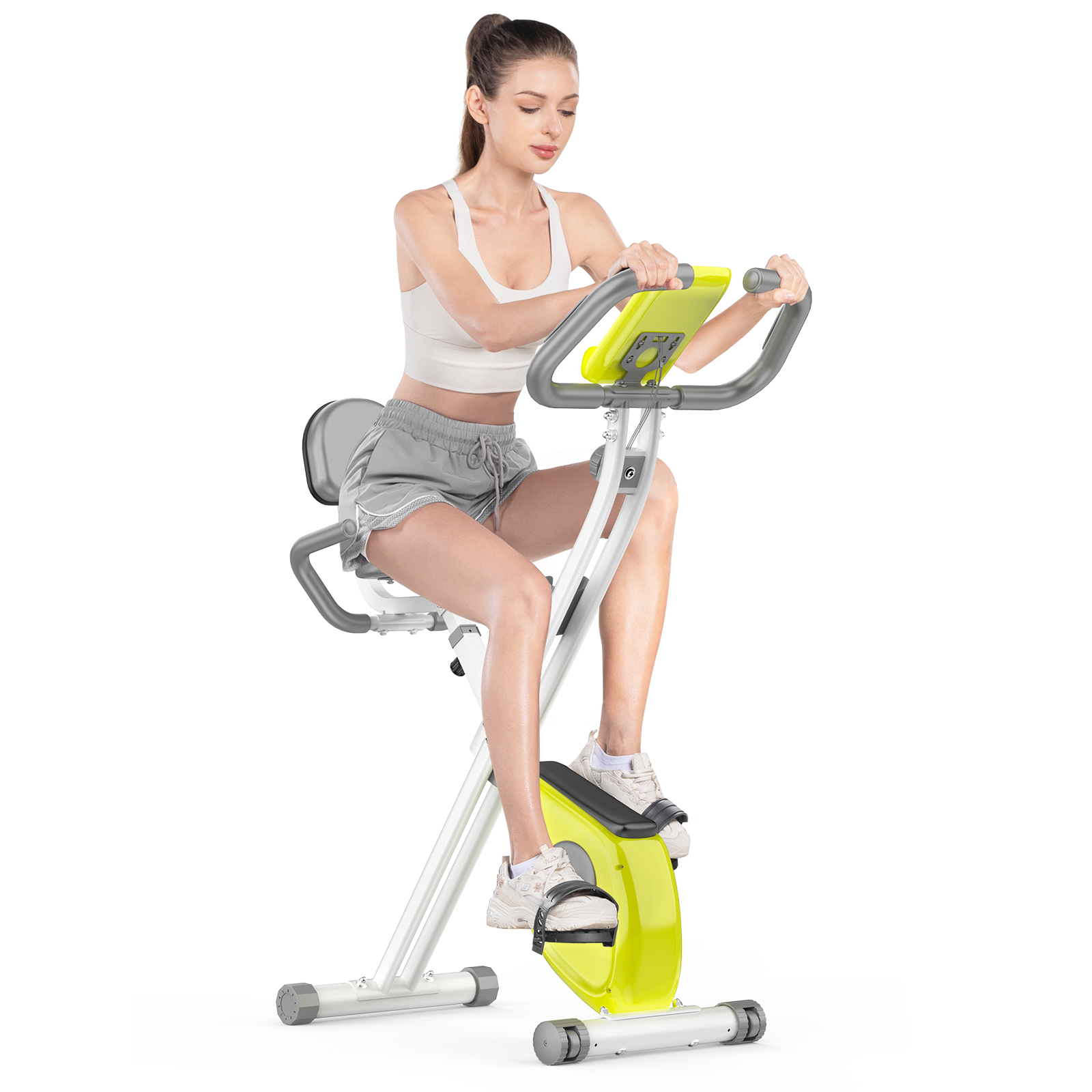 Kobieta ćwiczy na rowerze stacjonarnym. Ma na sobie biały top i szare szorty. Rower jest żółto-szary.