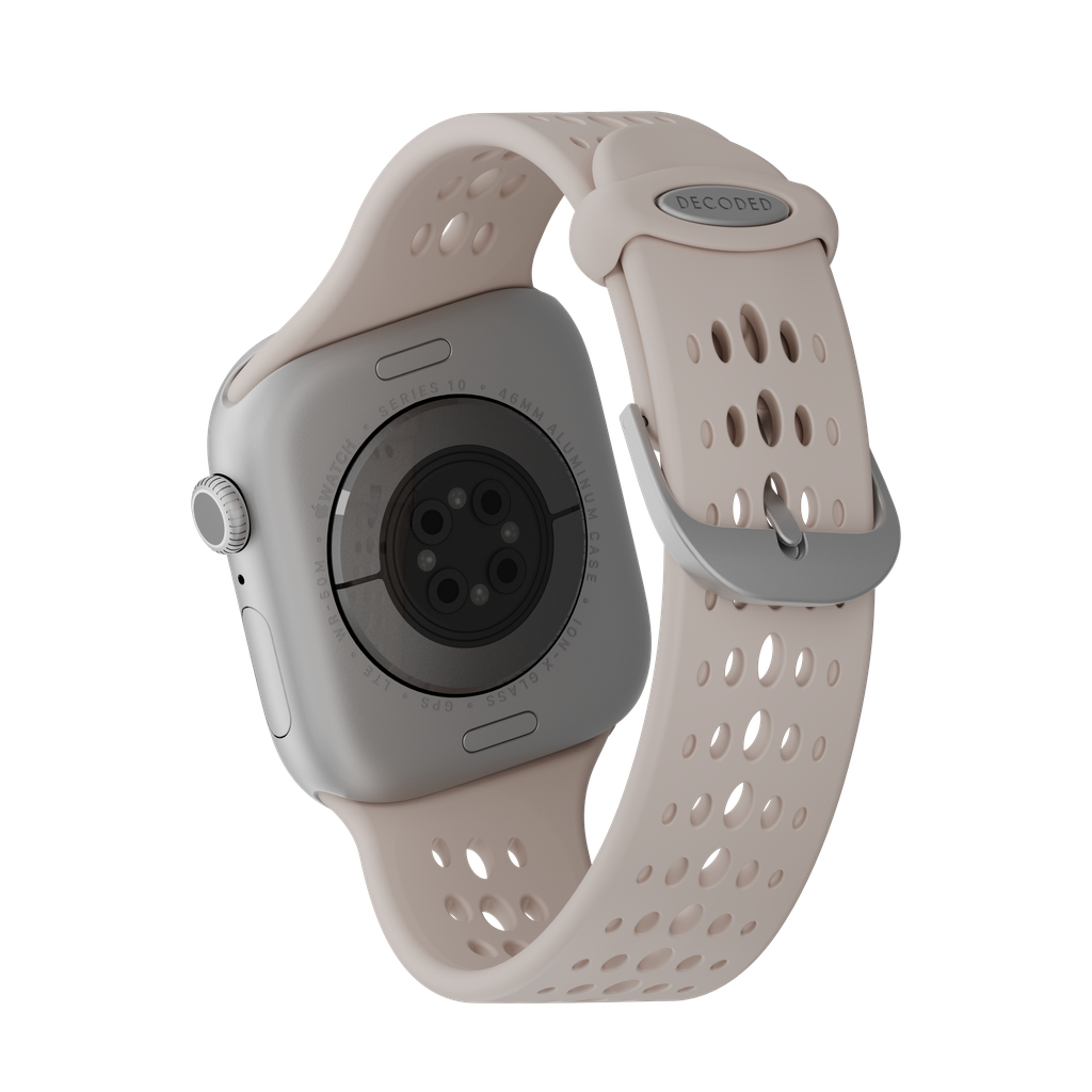 Primo piano di uno smartwatch con cinturino rosa chiaro. L'orologio è argentato e il cinturino perforato. Lo sfondo è nero.