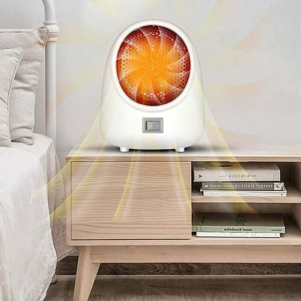 Ein weißer Elektroheizer auf einem Nachttisch aus Holz. Links ist ein Bett. Der Heizer ist an, mit orangem Licht.