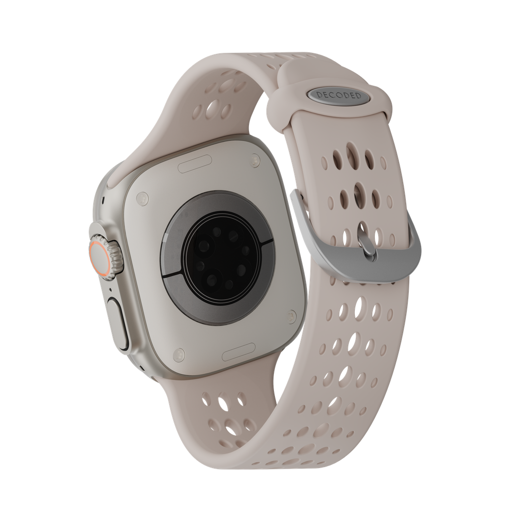 Primo piano di uno smartwatch, che mostra il retro e il cinturino. L'orologio è grigio chiaro, con un cinturino rosa chiaro e una fibbia argentata.