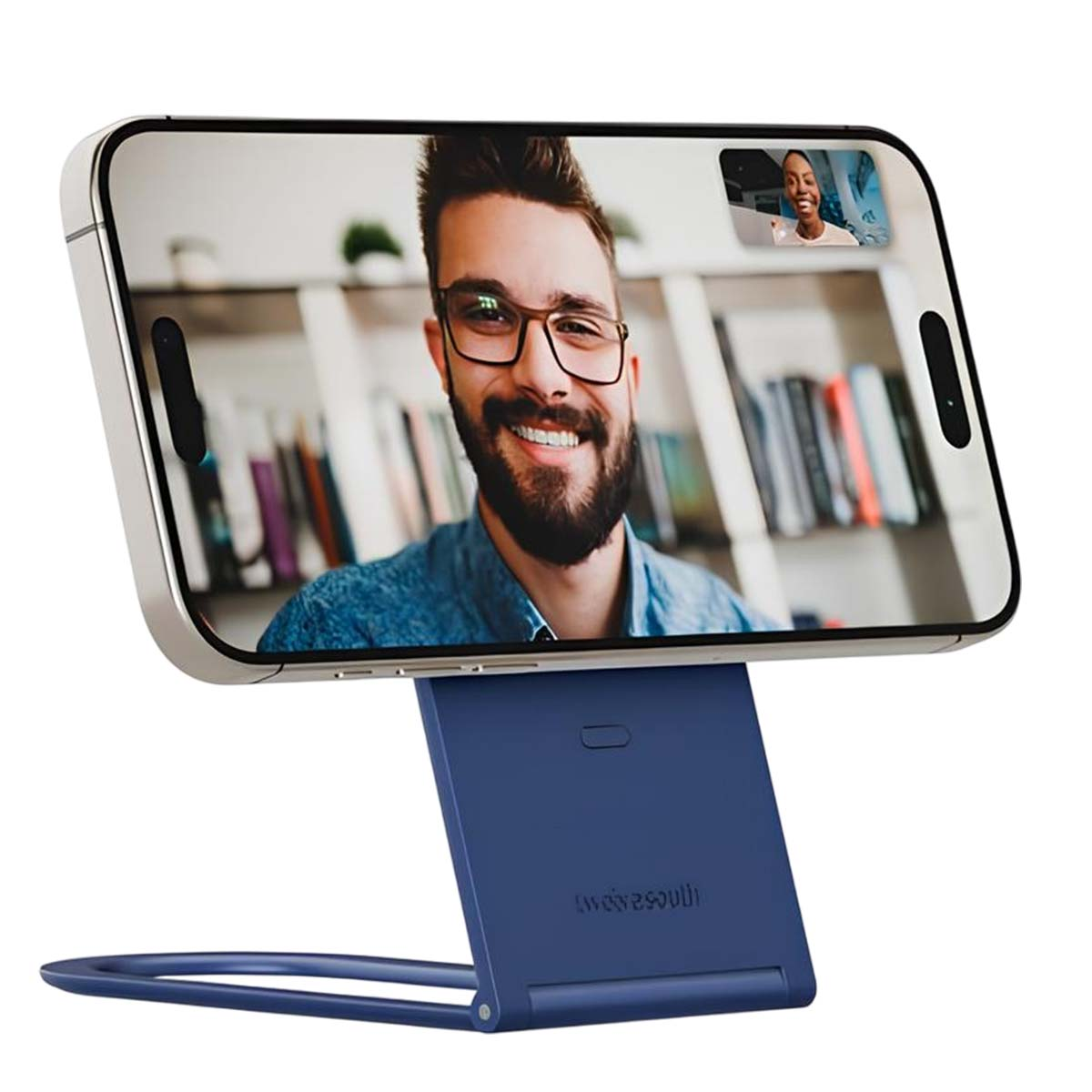 Telefono su supporto che mostra una videochiamata. Uomo con barba e occhiali sorride. Un'altra persona in una piccola finestra.