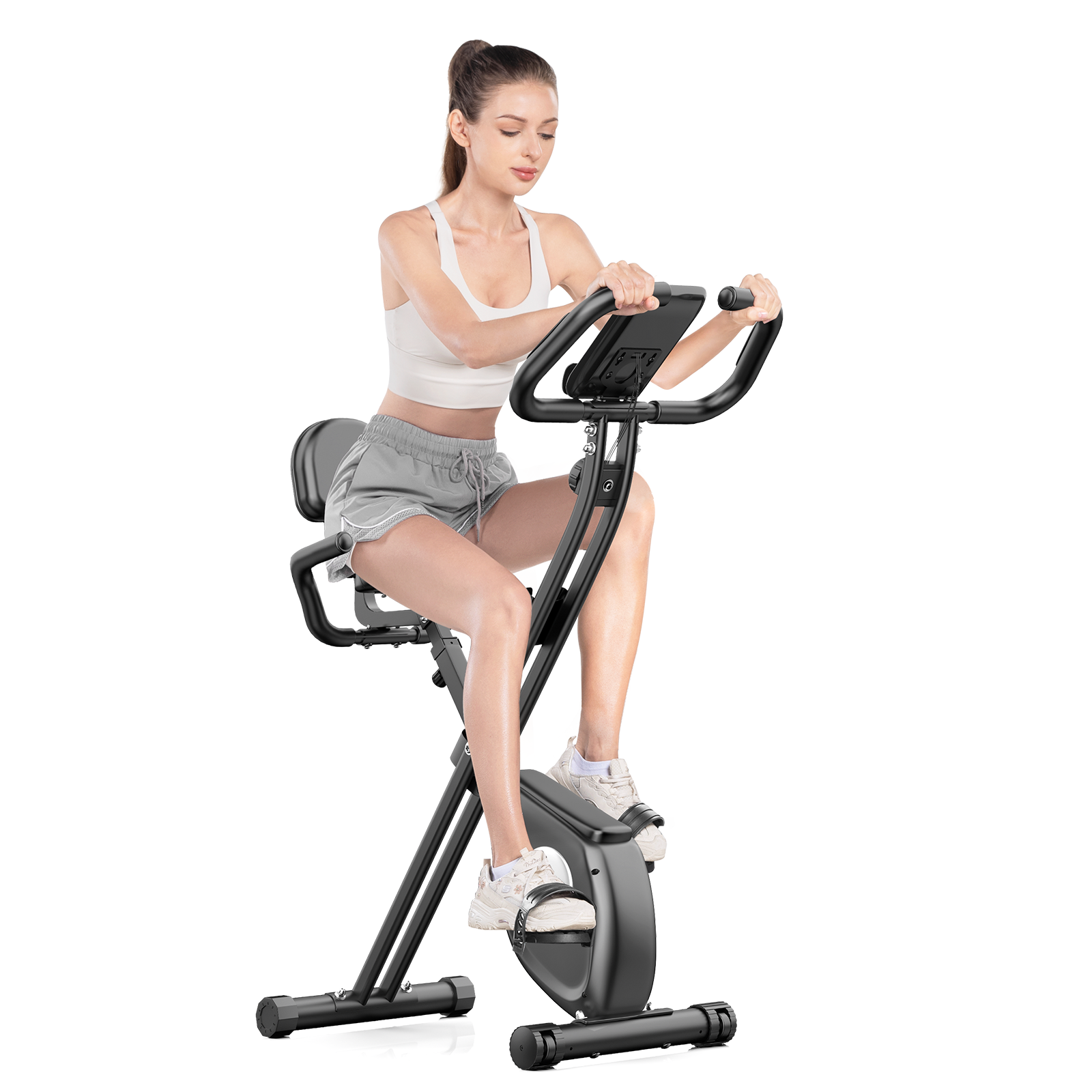 Kobieta jest na rowerze stacjonarnym. Ma na sobie biały top, szare szorty i białe buty. Rower jest czarny.