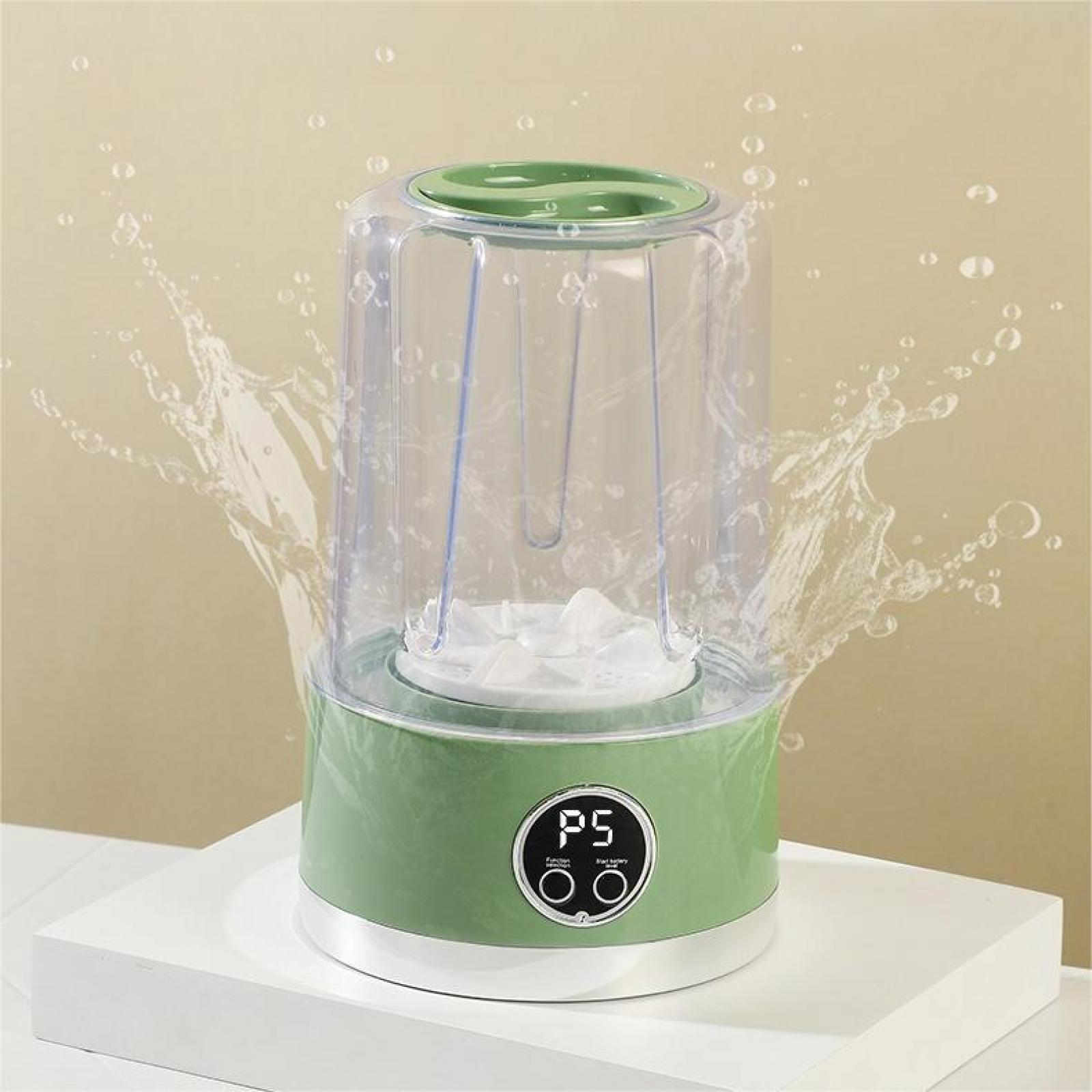 Ein grüner Mixer mit einem durchsichtigen Behälter. Wasser spritzt herum. Der Mixer steht auf einer weißen Oberfläche.