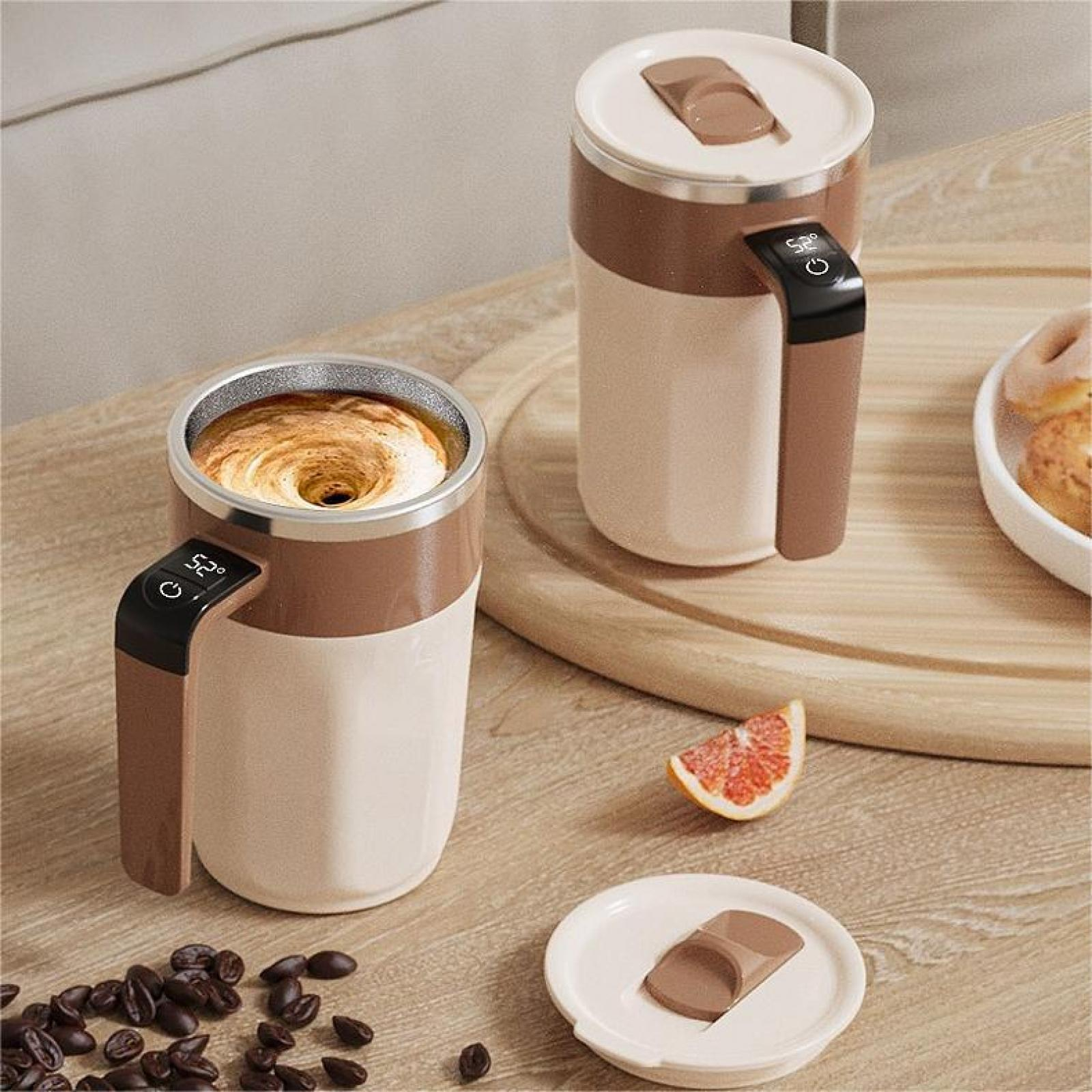 Zwei Kaffeetassen in Braun und Creme. Eine hat wirbelnden Kaffee, die andere einen Deckel. Kaffeebohnen, Orangenscheibe.