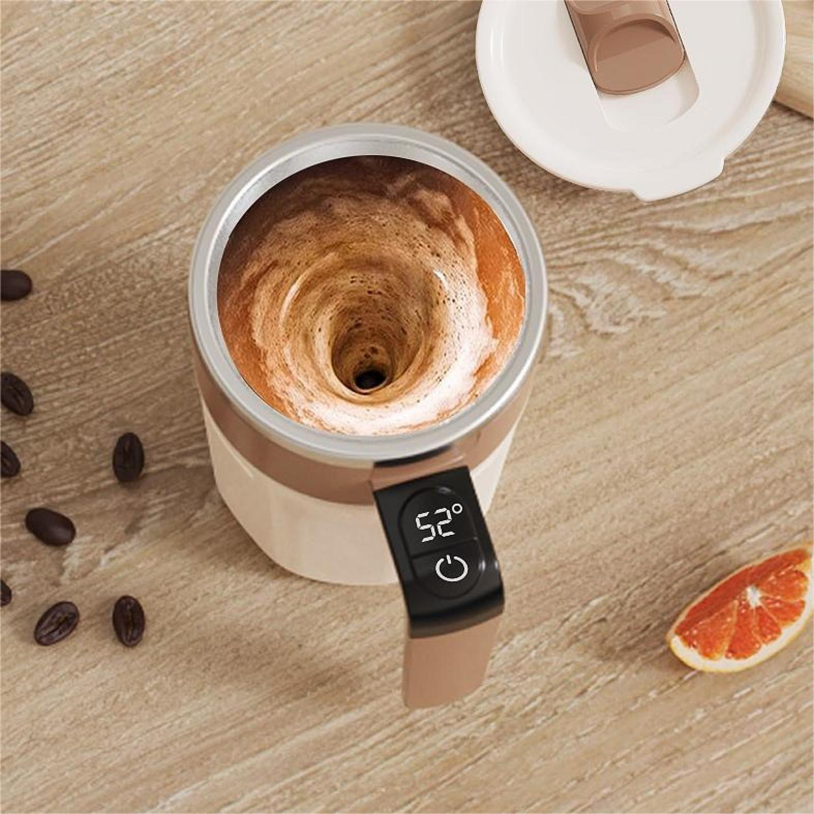 Ein Kaffeebecher mit einem wirbelnden Getränk. Ein Digitaldisplay zeigt 52 Grad. Kaffeebohnen und eine Orangenscheibe sind in der Nähe.