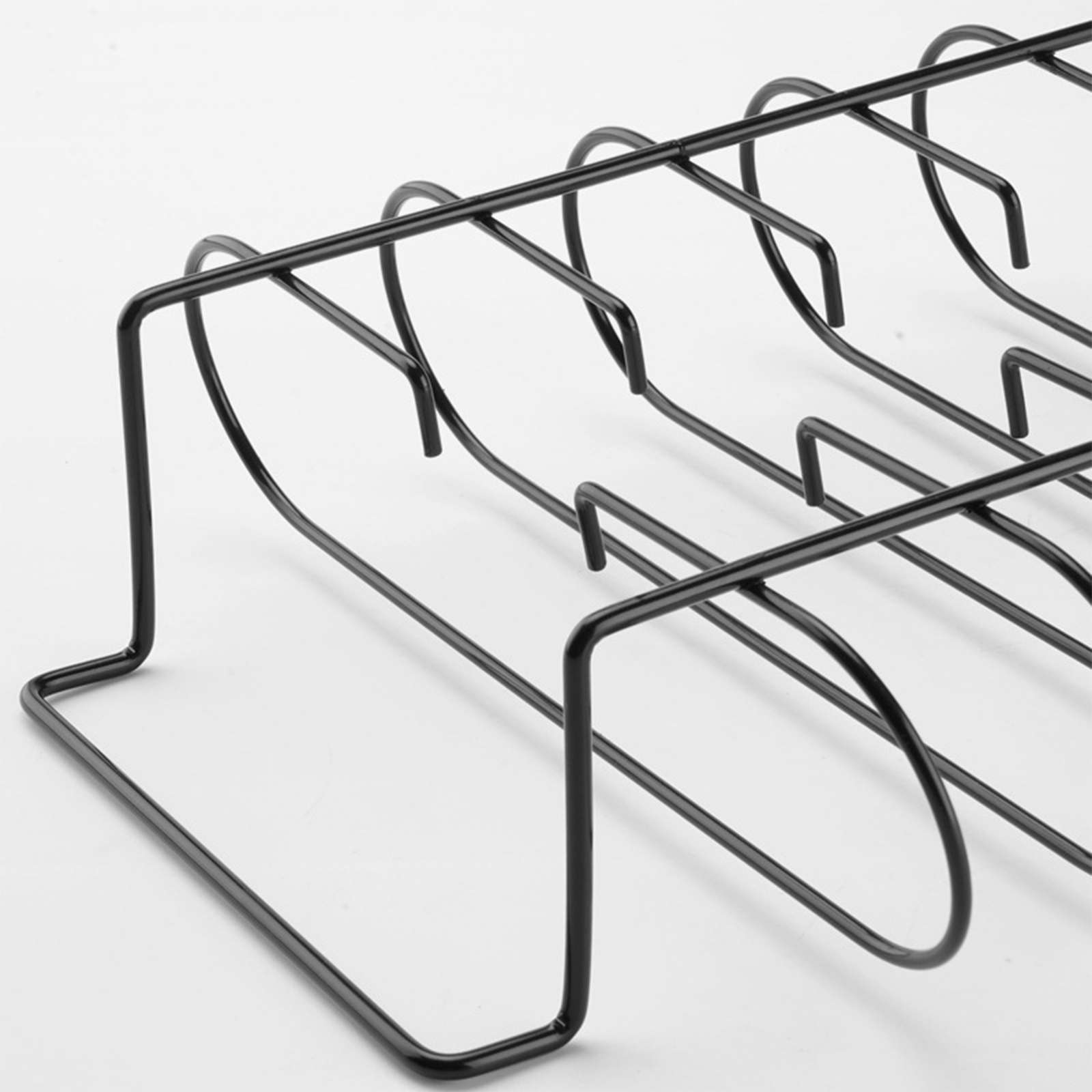 Nahaufnahme eines schwarzen Metallgestells mit gebogenen Stützen auf weißem Hintergrund.