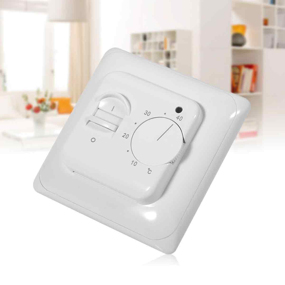 Ein weißes Thermostat mit Drehregler und Schieber wird angezeigt. Es ist an einer Wand mit hellem Hintergrund montiert.